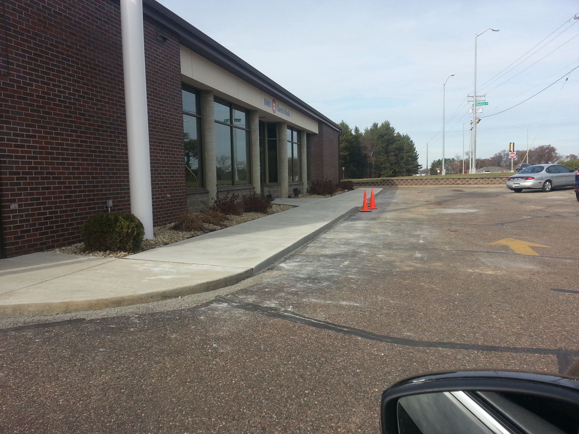 Brick building beside an empty parking lot with orange traffic cones and a sidewalk