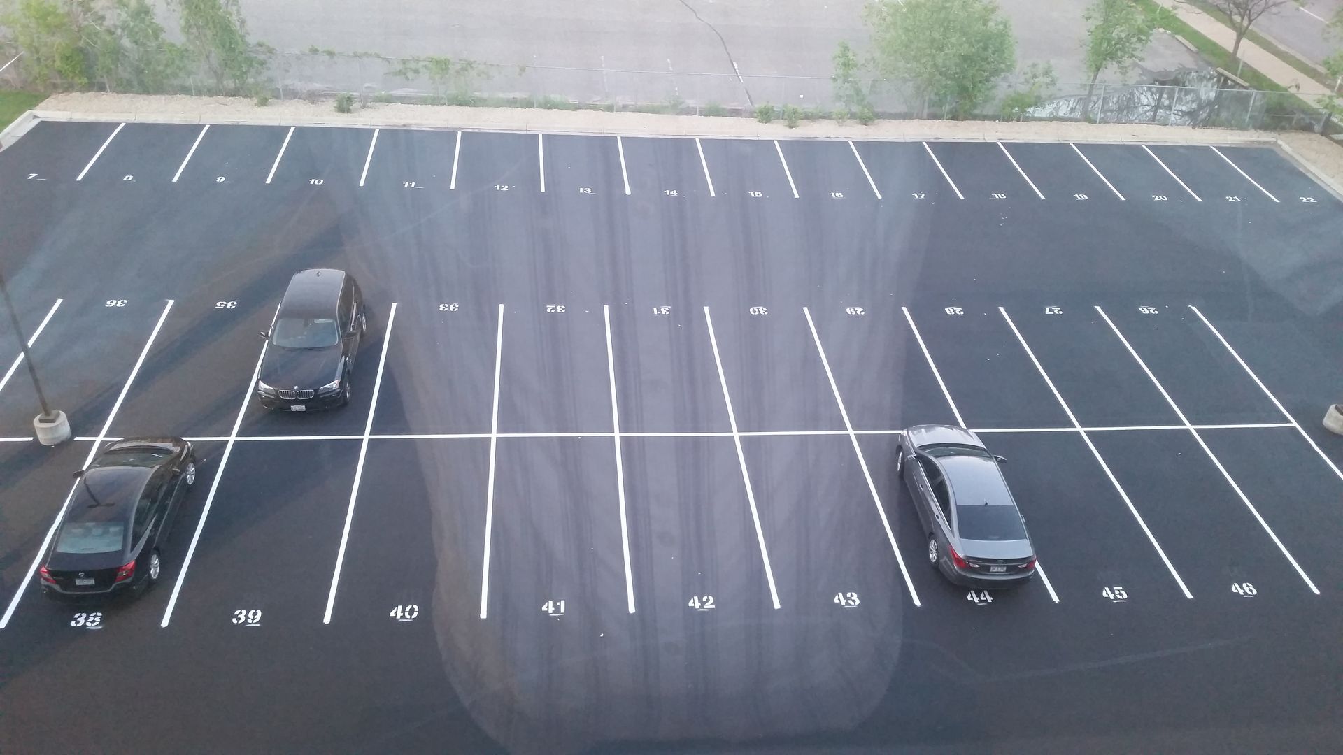 Almost empty parking lot with three cars parked on the left side and one near the center right.