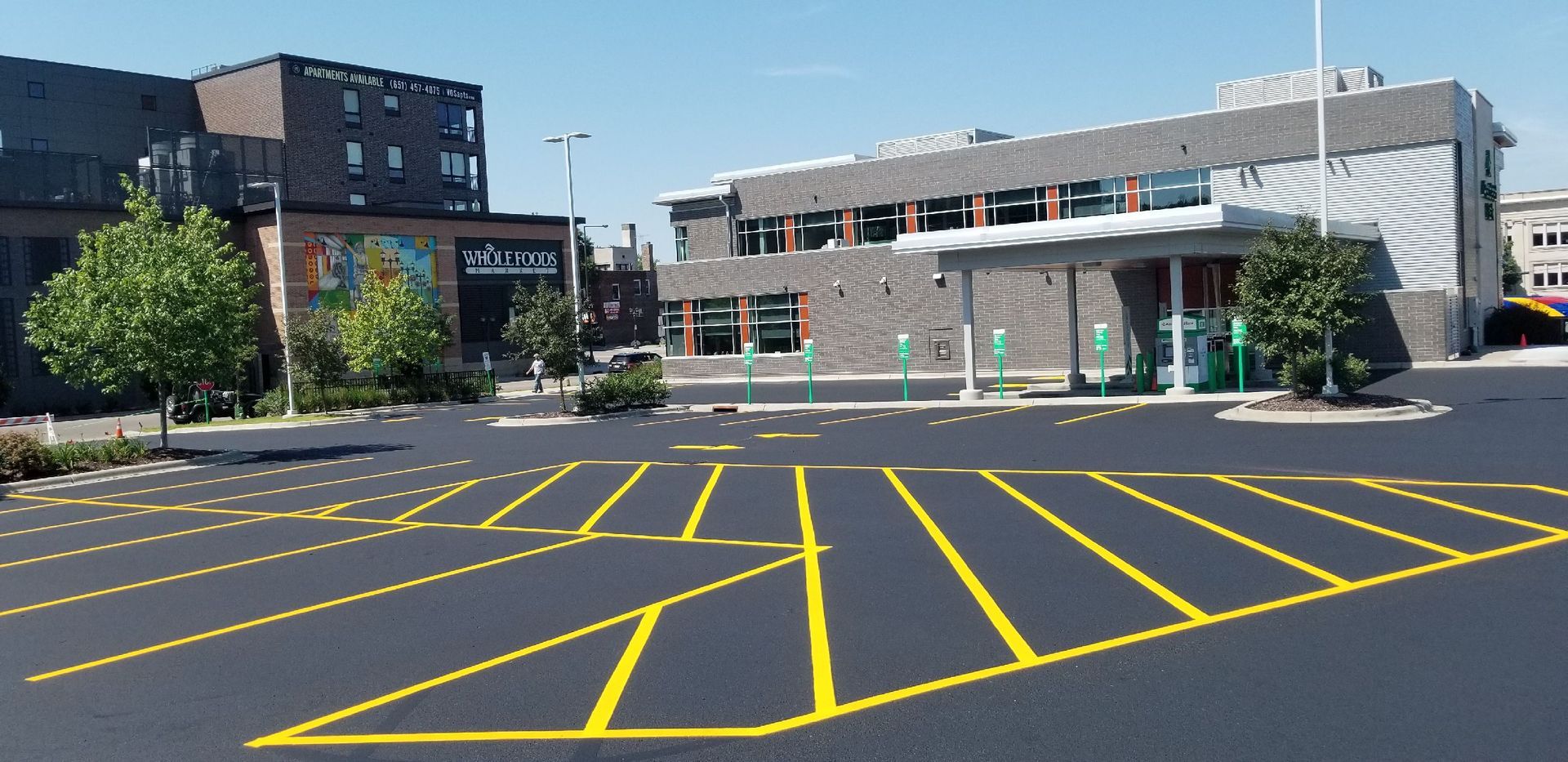 Empty parking lot with yellow lines in front of a building under a blue sky.