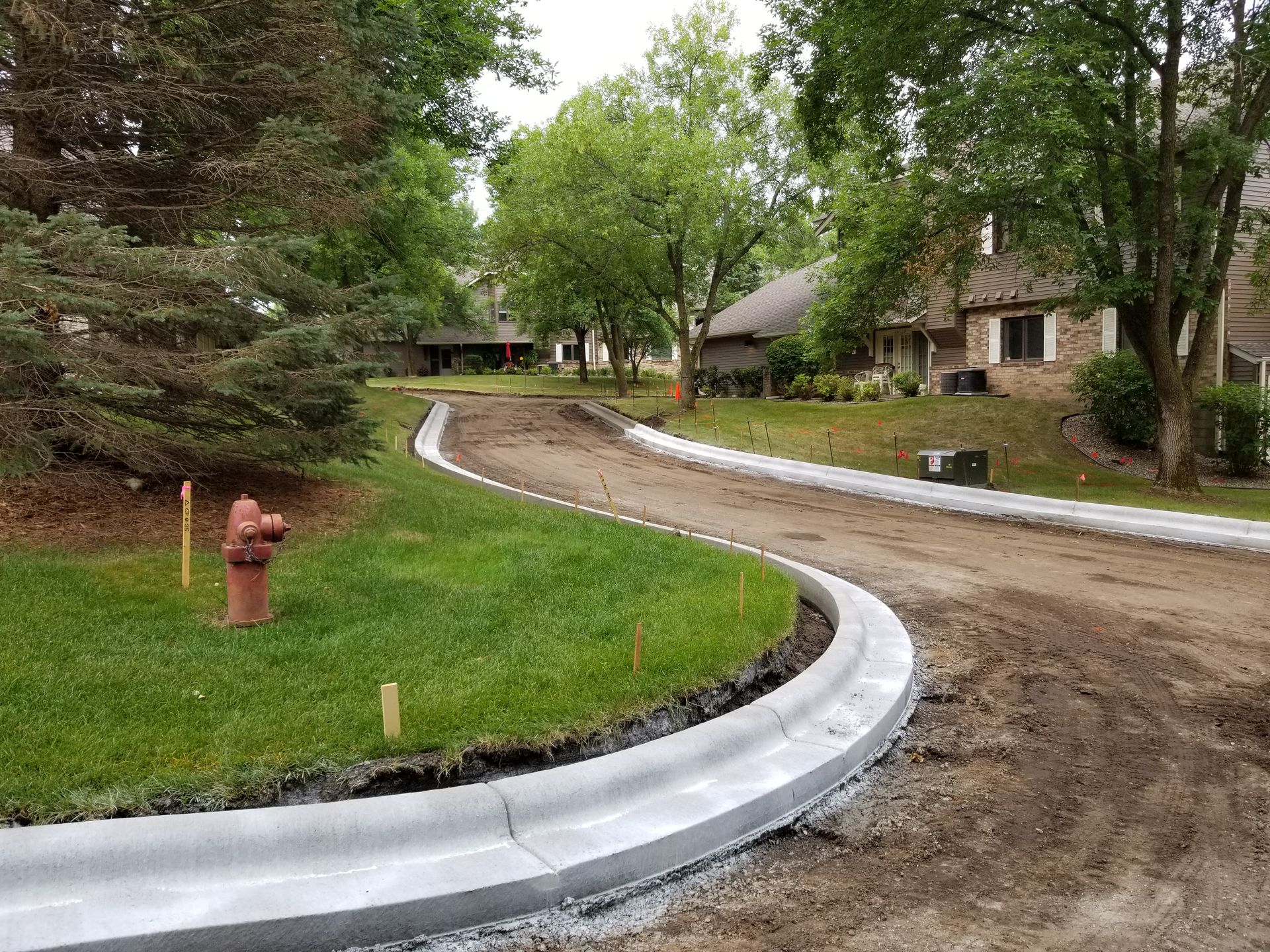 Curving gravel driveway beside lawns and trees, with a red fire hydrant in the foreground.