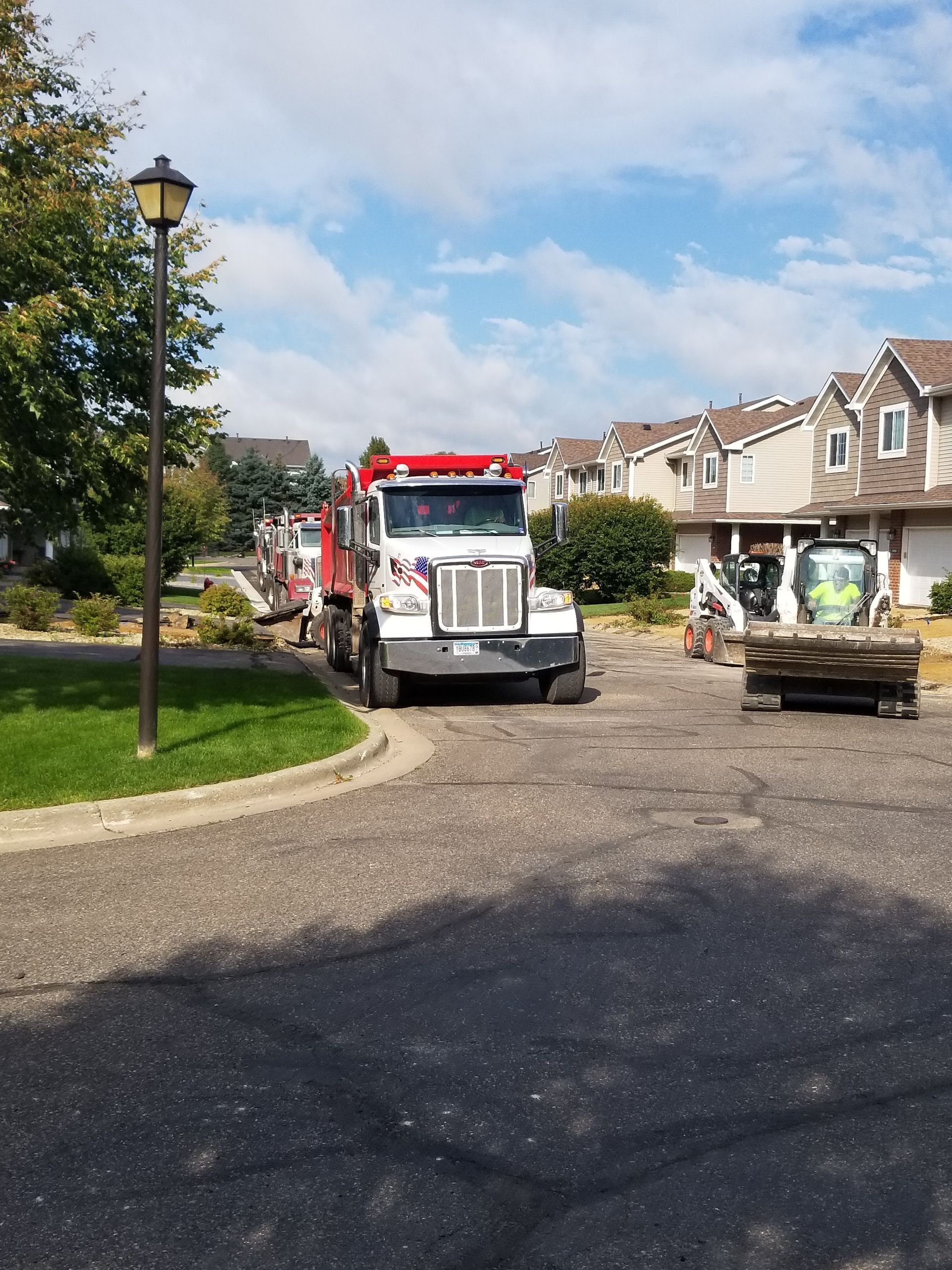 Red truck parked on a suburban street with workers and landscaping materials nearby