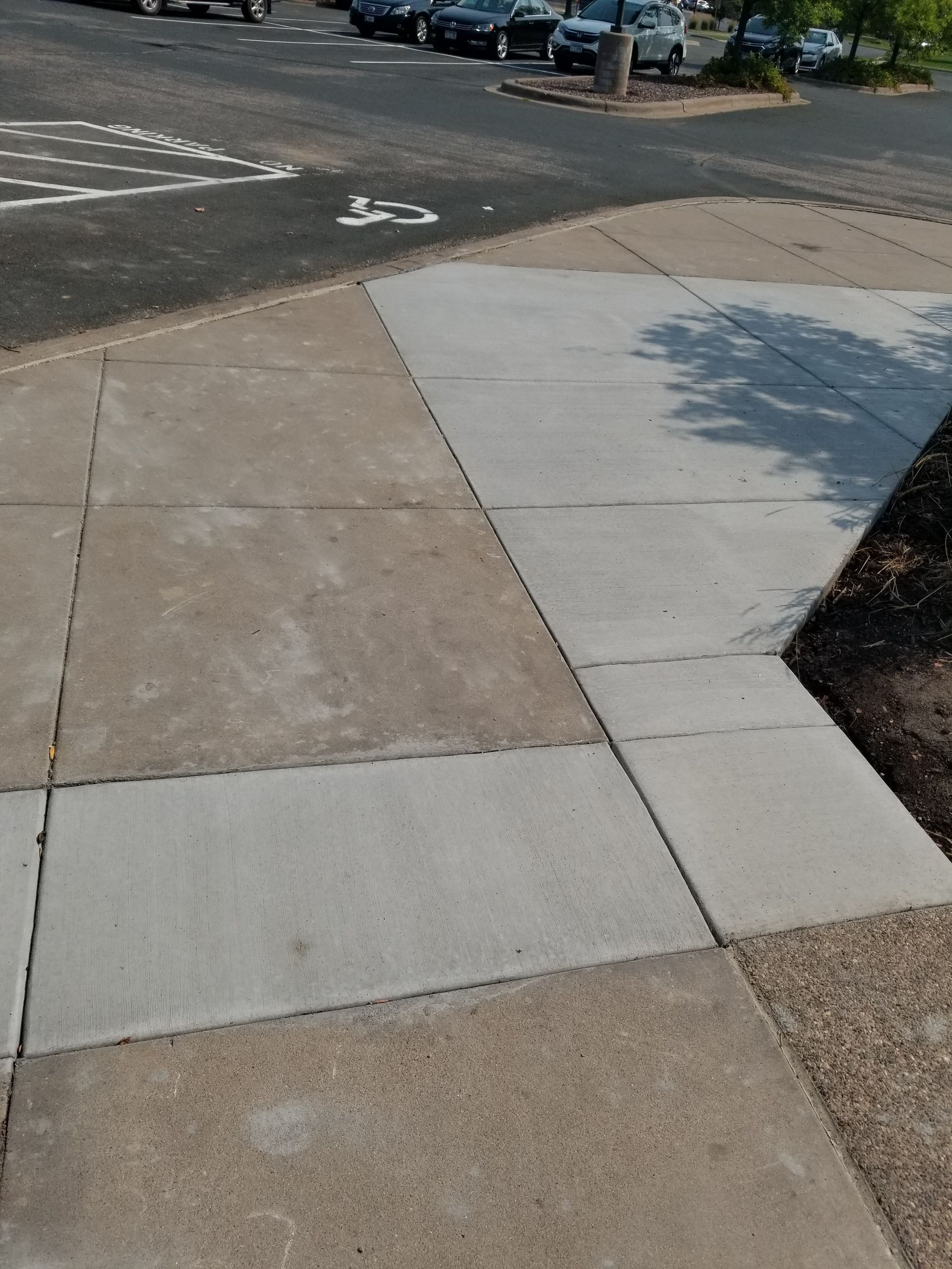 Accessible sidewalk curb ramp with gray concrete panels at a street corner