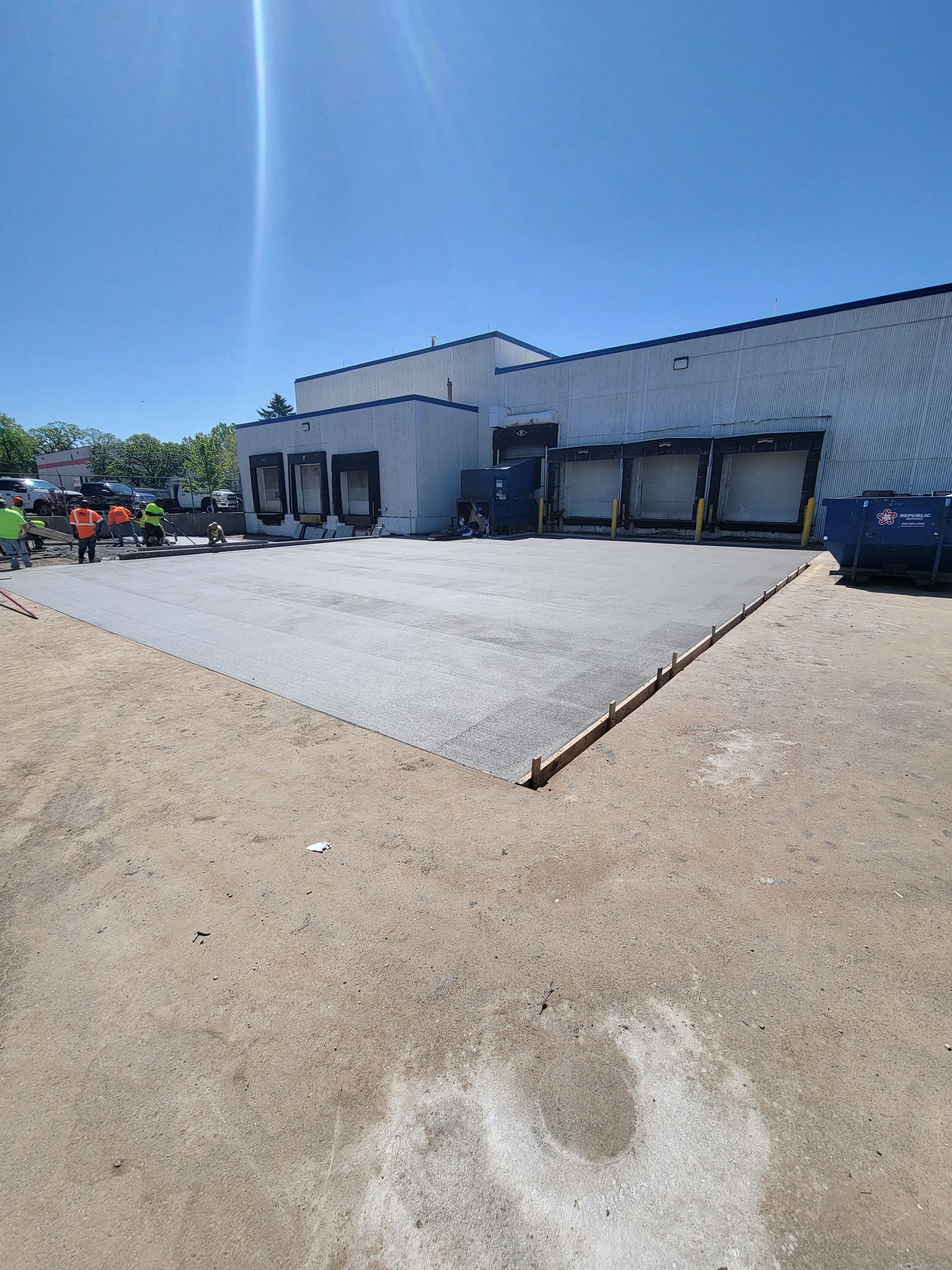 Industrial warehouse with loading docks, paved lot, and blue sky