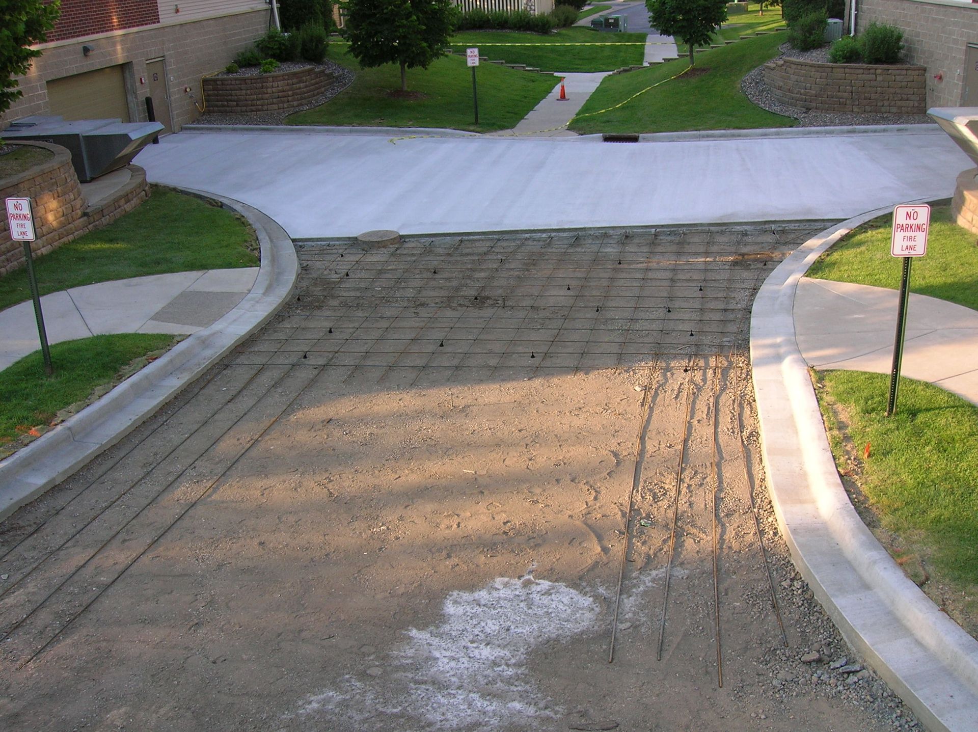 Steep residential driveway with a textured concrete surface and curving curbs between manicured lawns