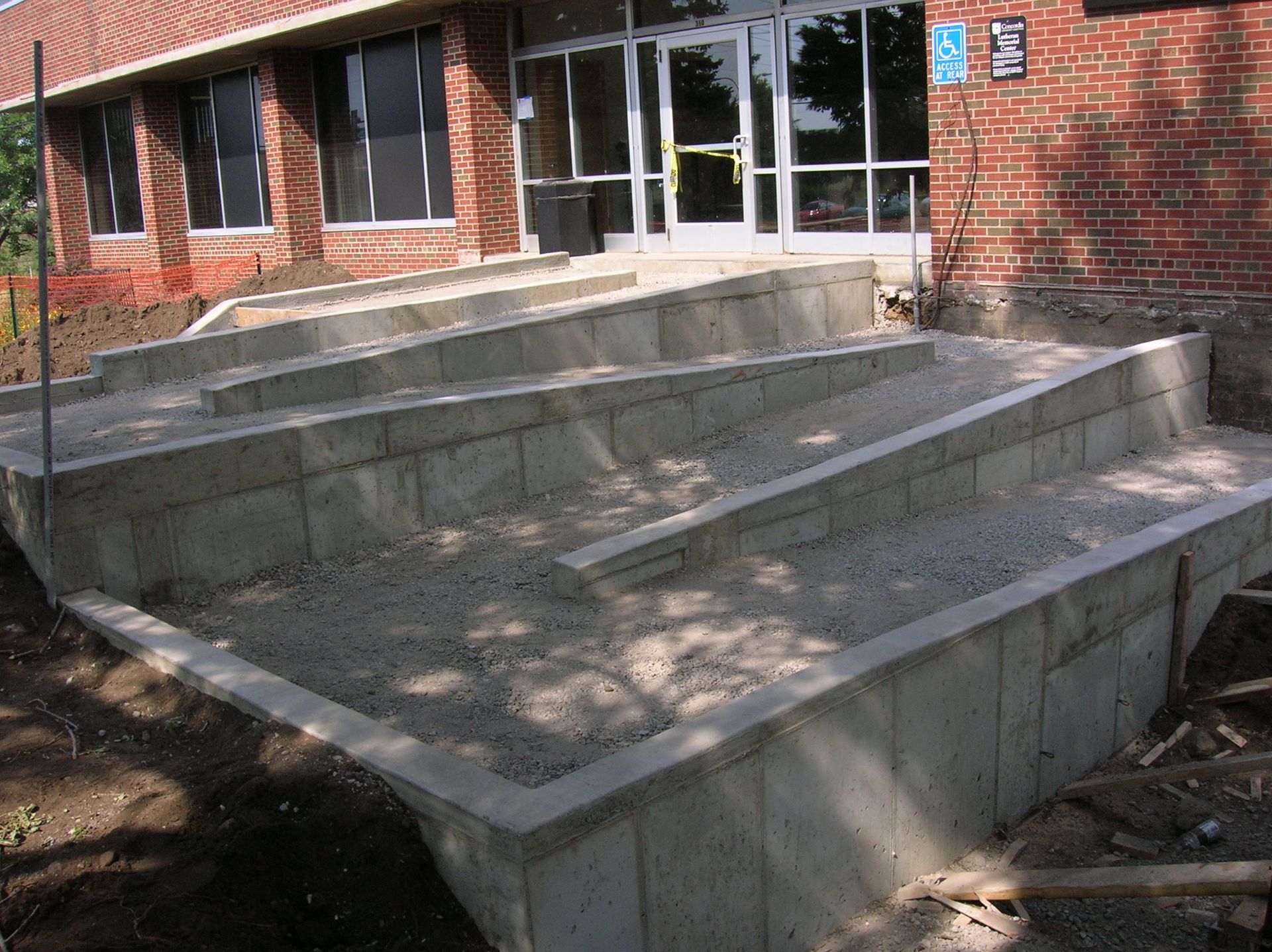Concrete wheelchair ramp and steps leading to a brick building entrance