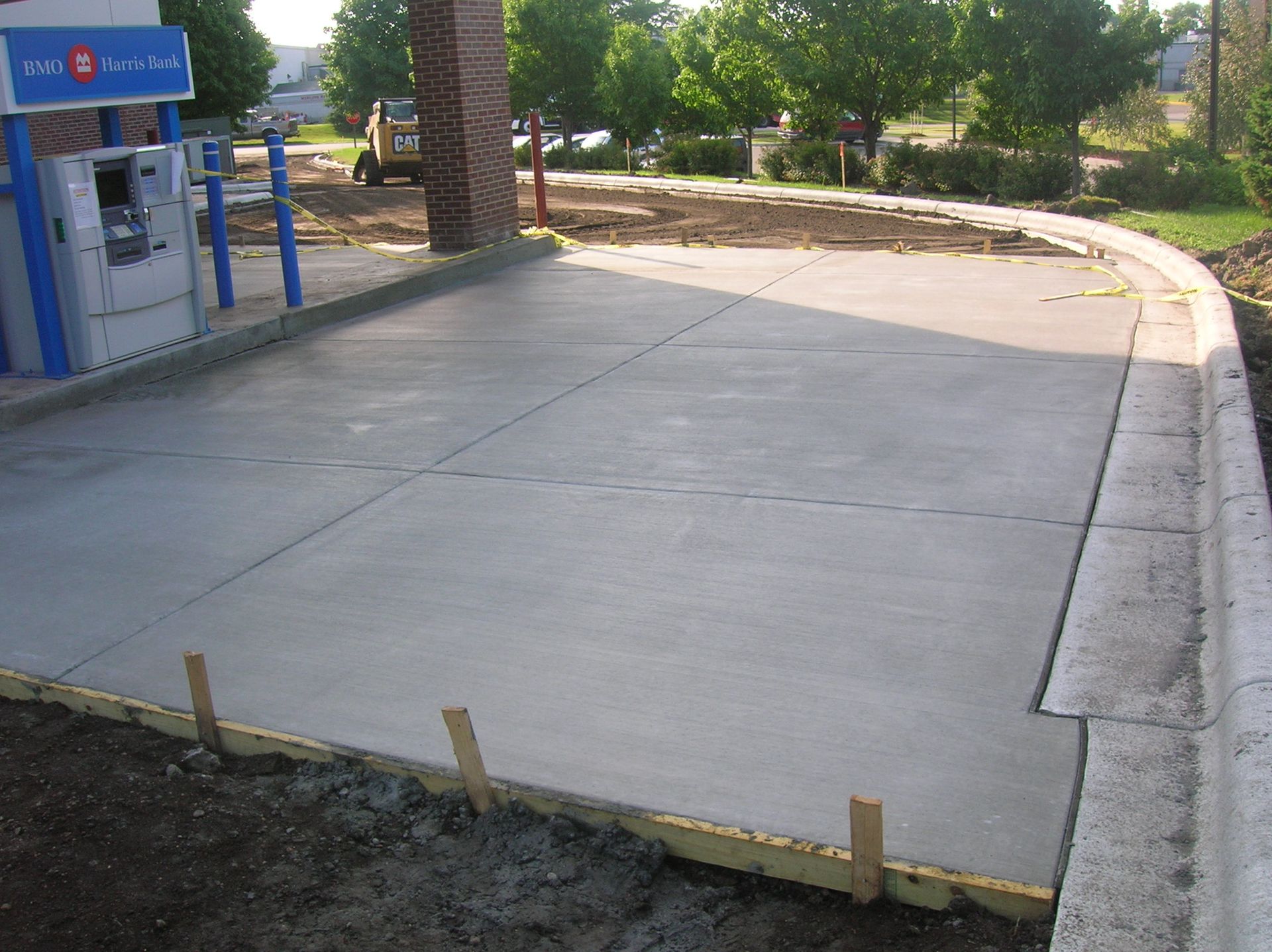 Freshly poured concrete slab at a gas station, with forms still visible along the edge.