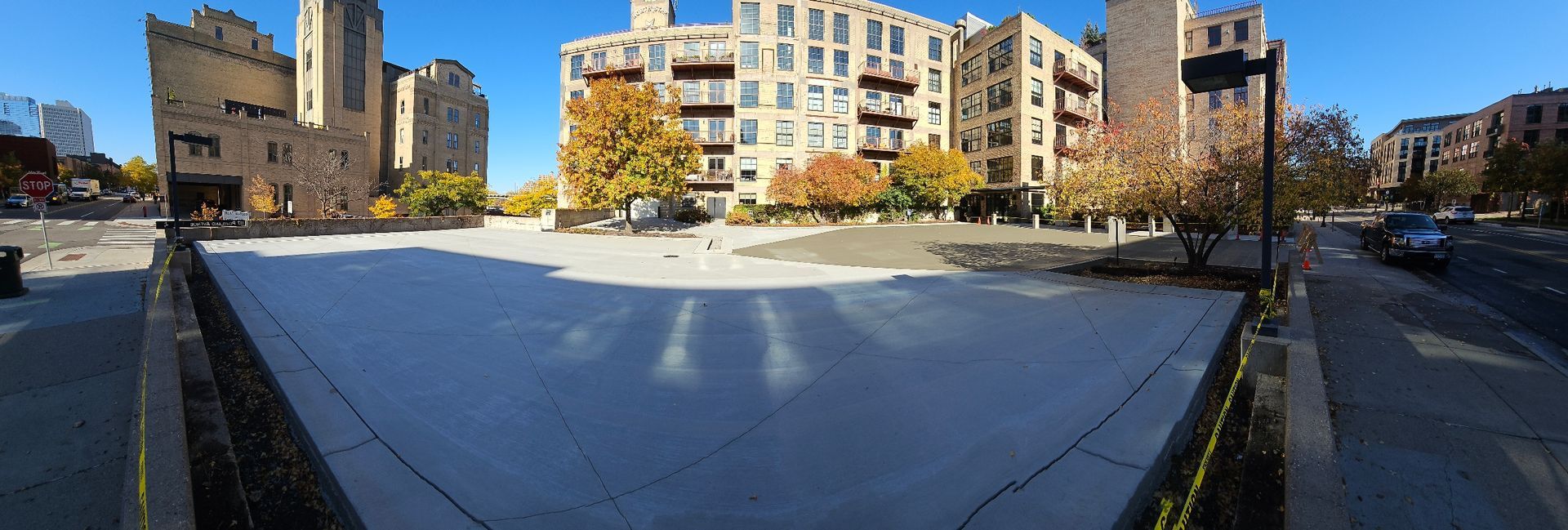 Sunny urban courtyard with apartment buildings, a castle-like tower, and trees in autumn