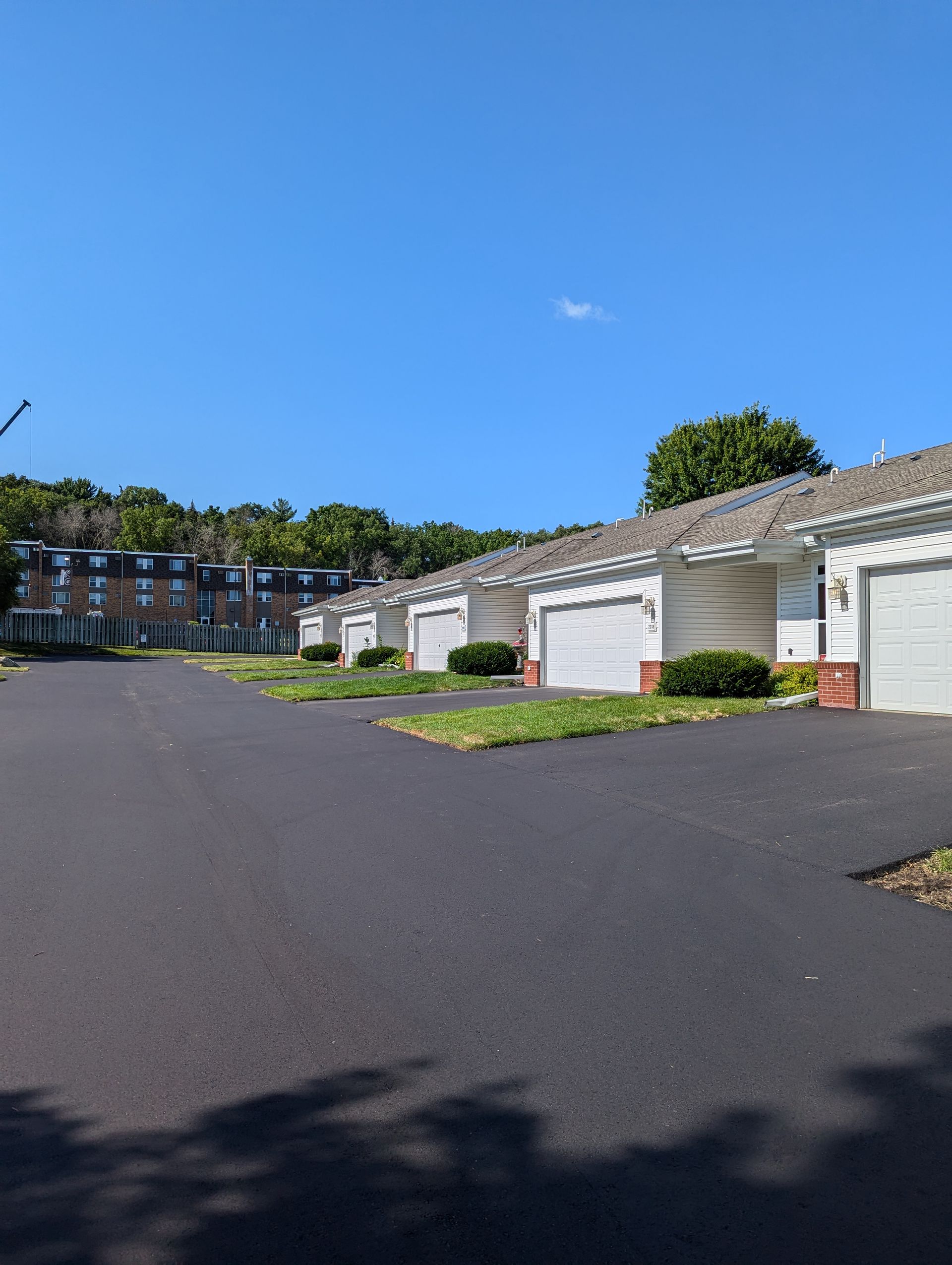 Apartment garages along a quiet paved drive under a clear blue sky