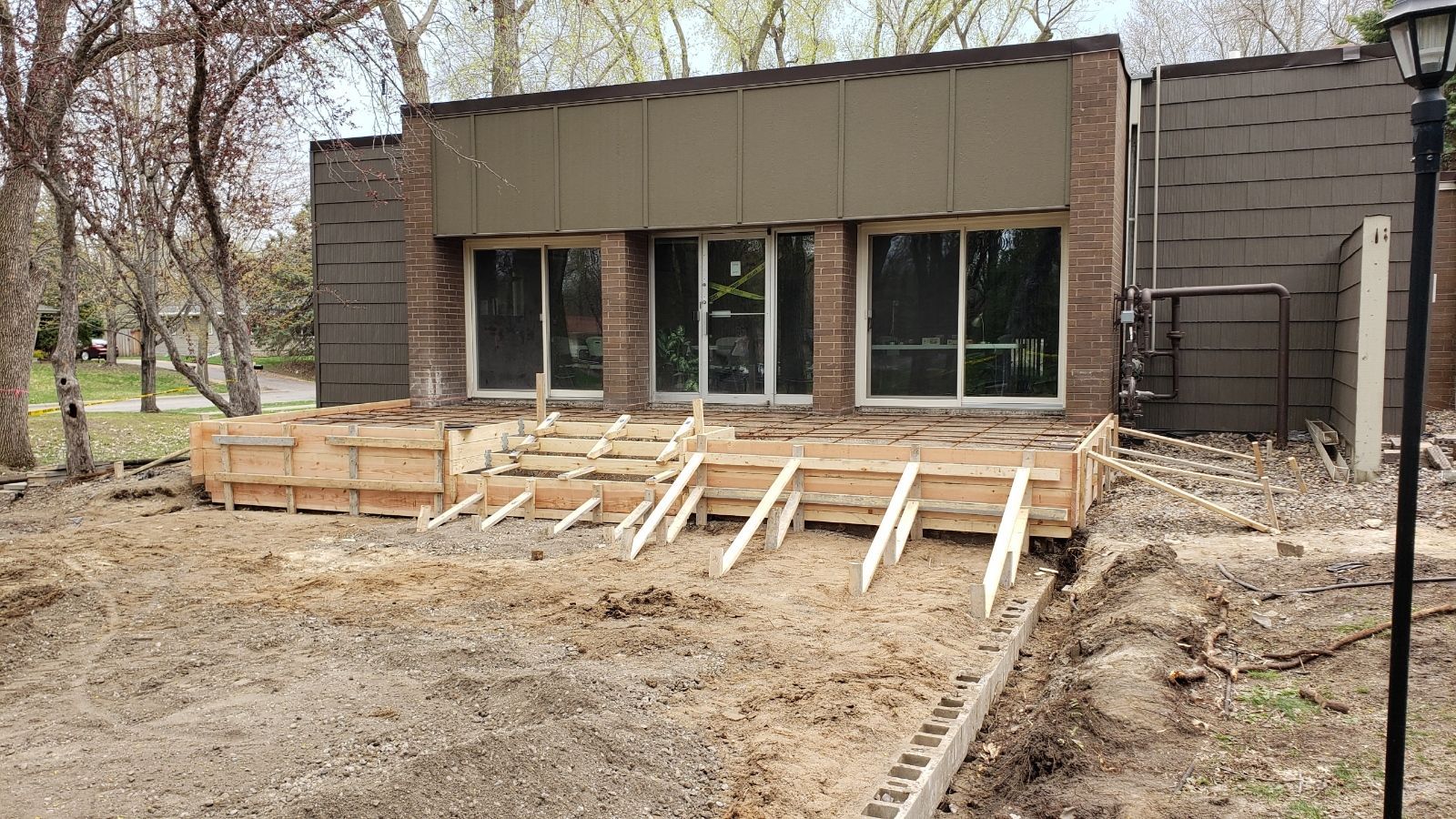 Outdoor building renovation with wood framing and stacked lumber in front of a brick building