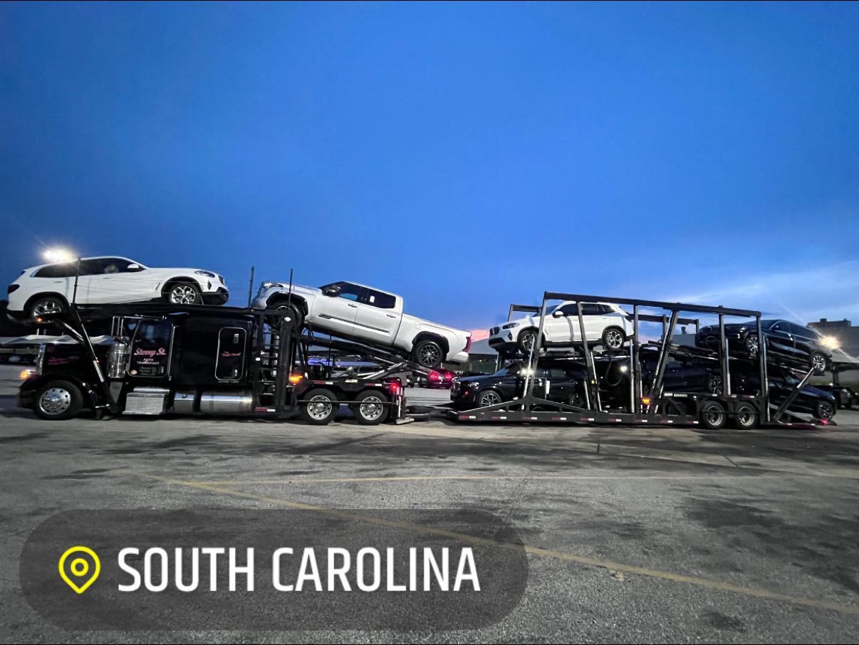 Car haulers stacked with vehicles under a blue sky in South Carolina.