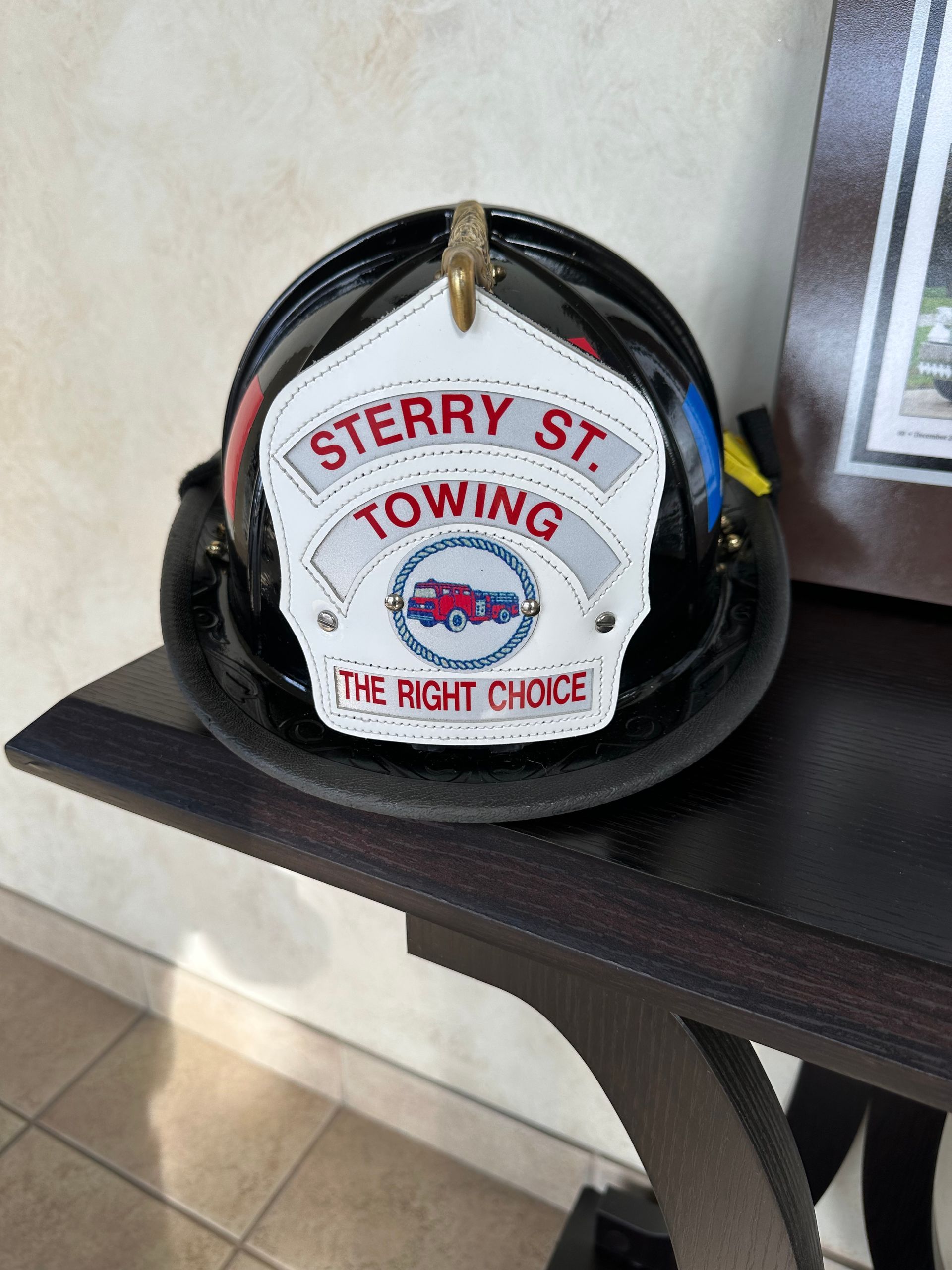 Black helmet with a “STERRY ST. TOWING” logo on a shelf indoors.