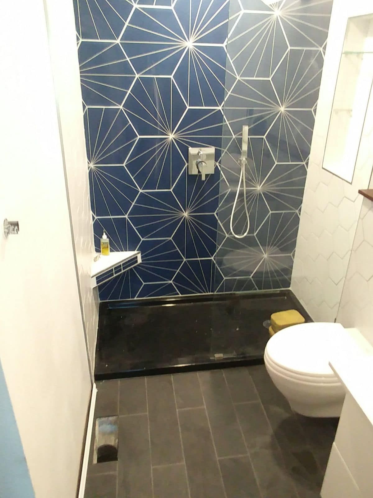 A bathroom with a toilet, shower and blue tiles