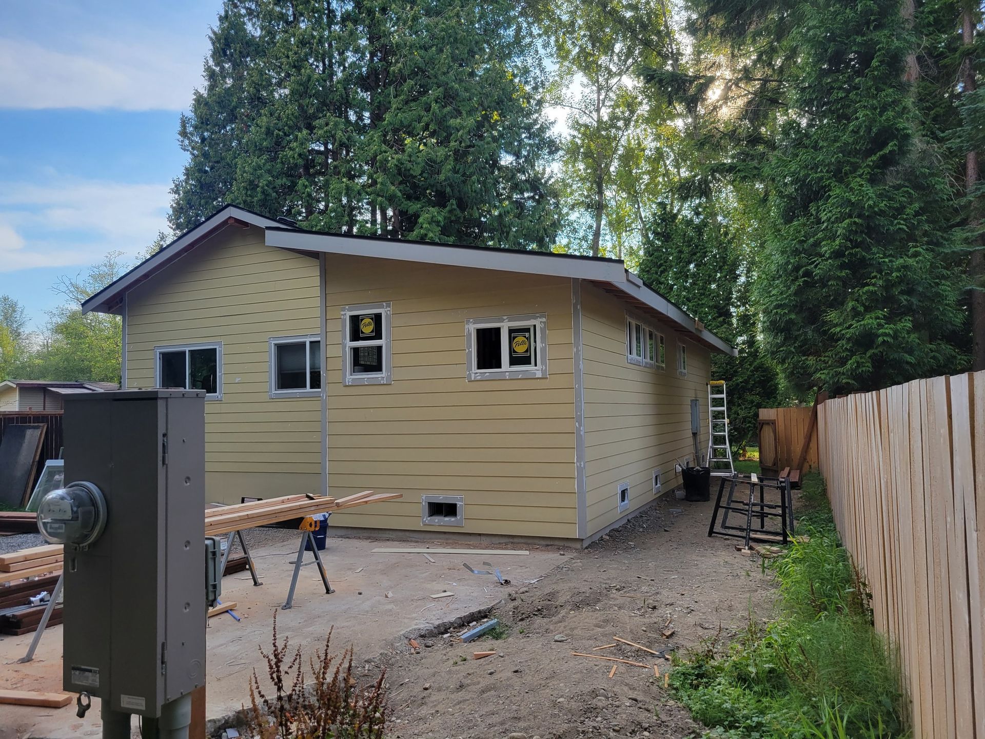 A yellow house is being built next to a wooden fence