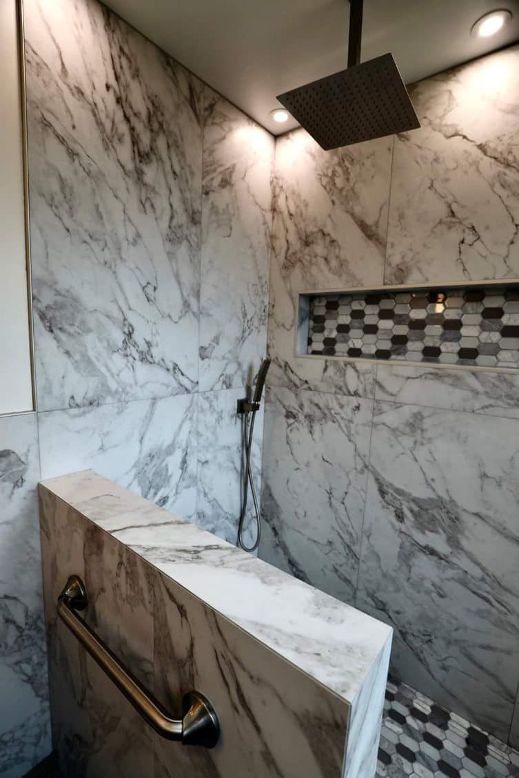 A bathroom with marble walls and a shower head
