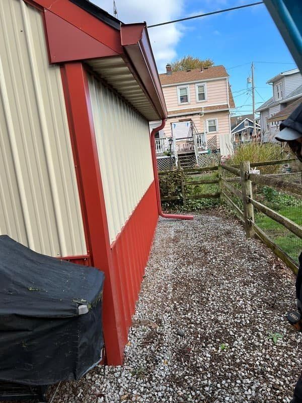 Red and cream building exterior with a gravel path and wooden fence.