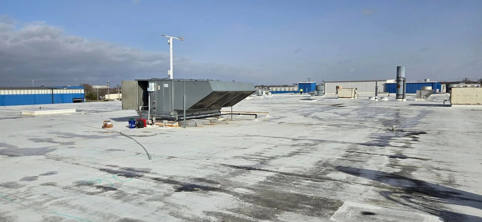 A rooftop with equipment. A bright blue sky. The roof is covered with snow.