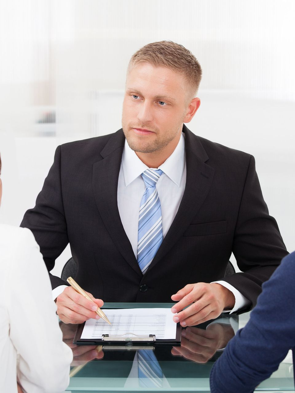 Business meeting with a man in a black suit taking notes at a glass table