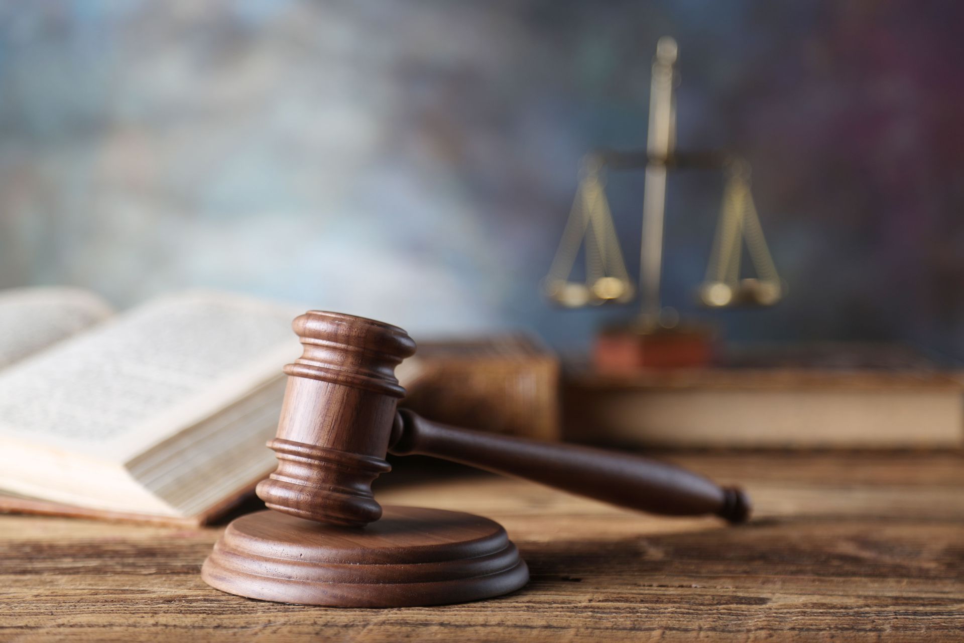 Judge’s gavel on a wooden desk with scales of justice and an open book in the background