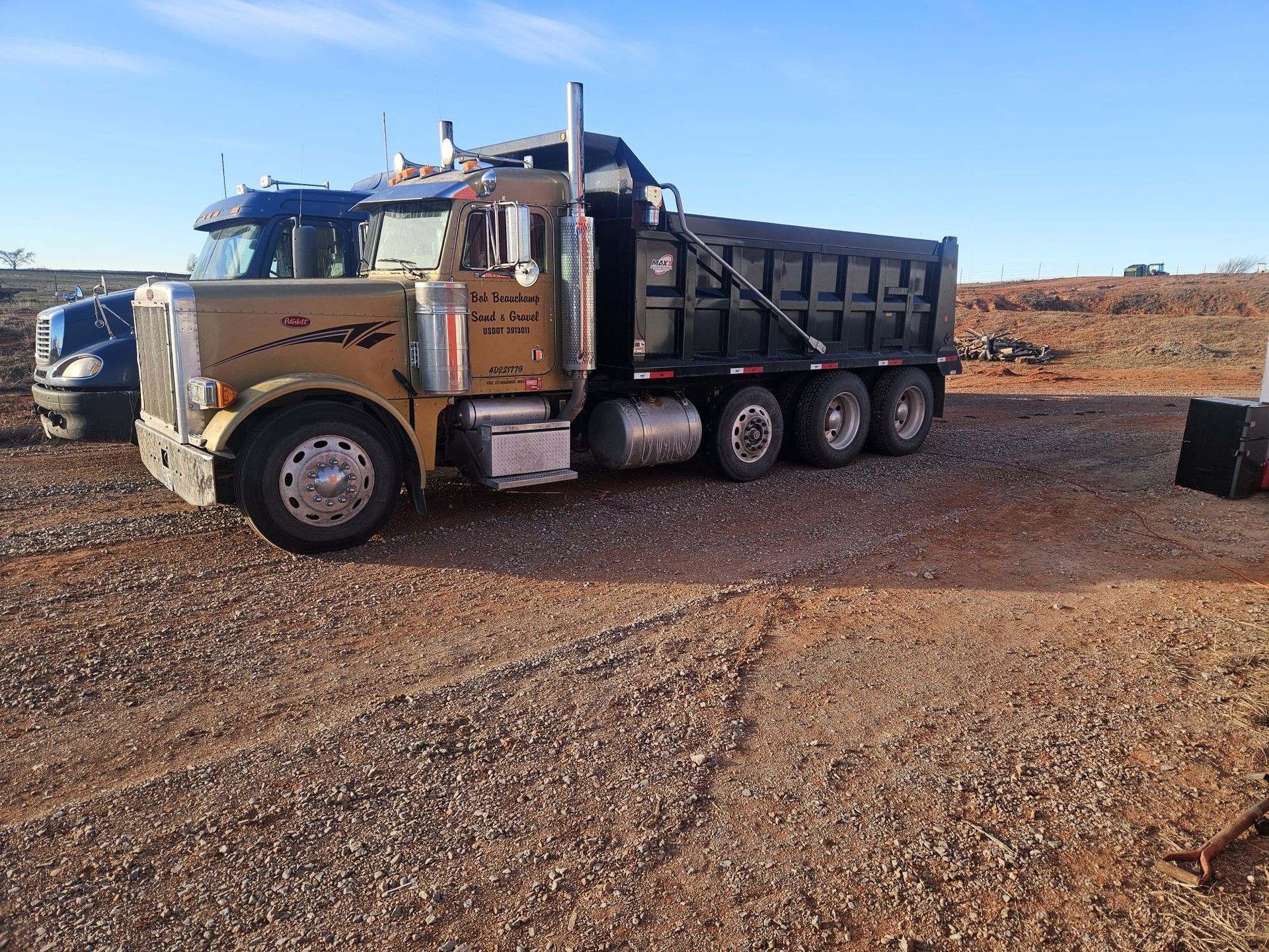 A dump truck is parked in a gravel lot.