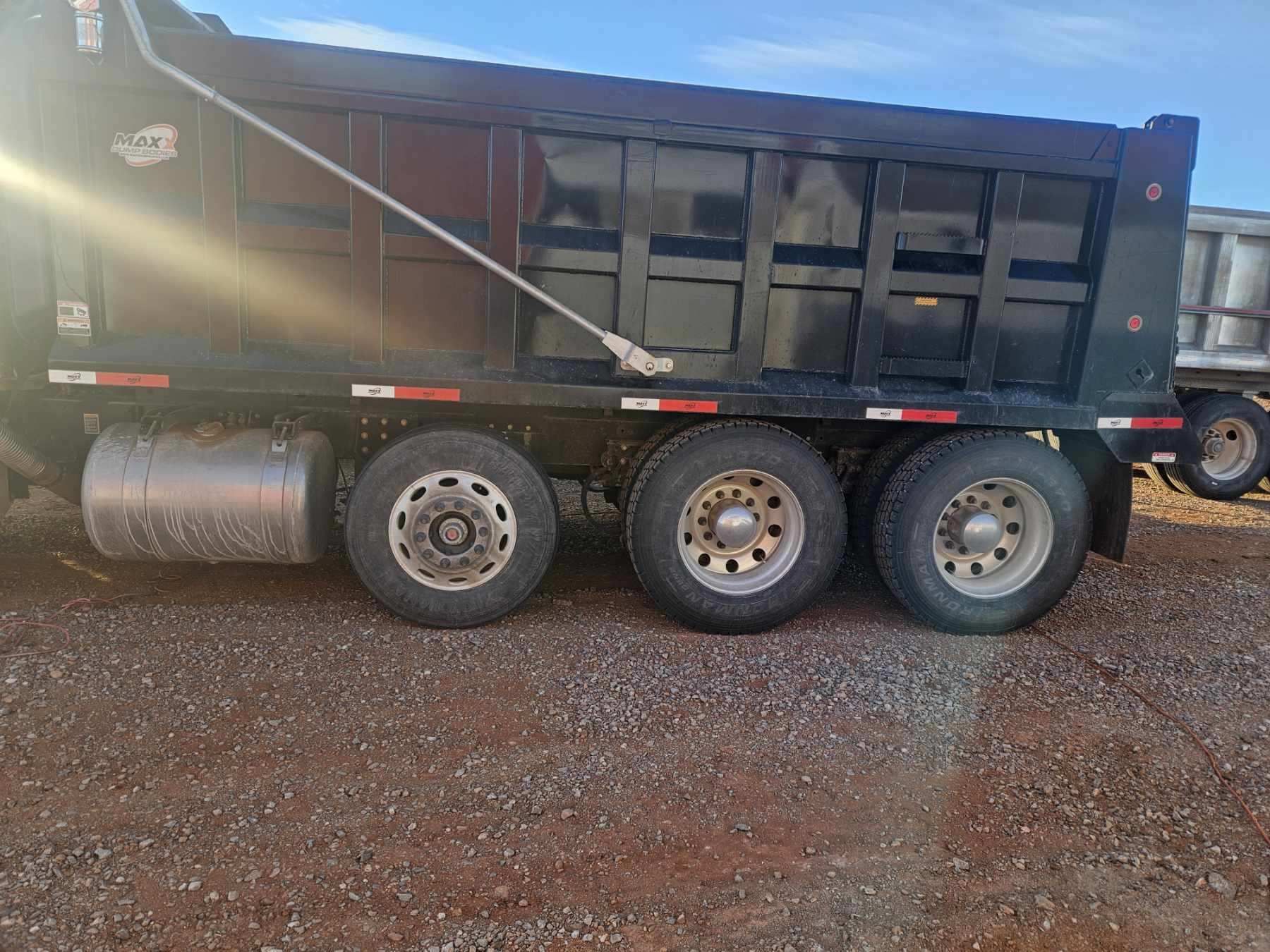 A dump truck is parked on a gravel road.