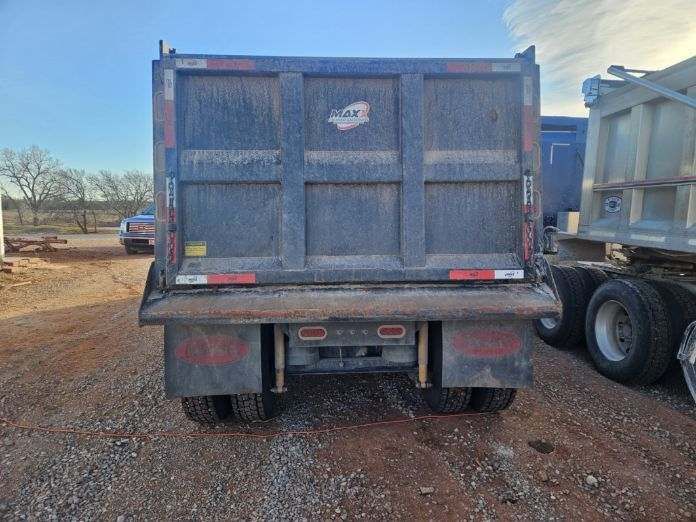 A dump truck is parked in a gravel lot.