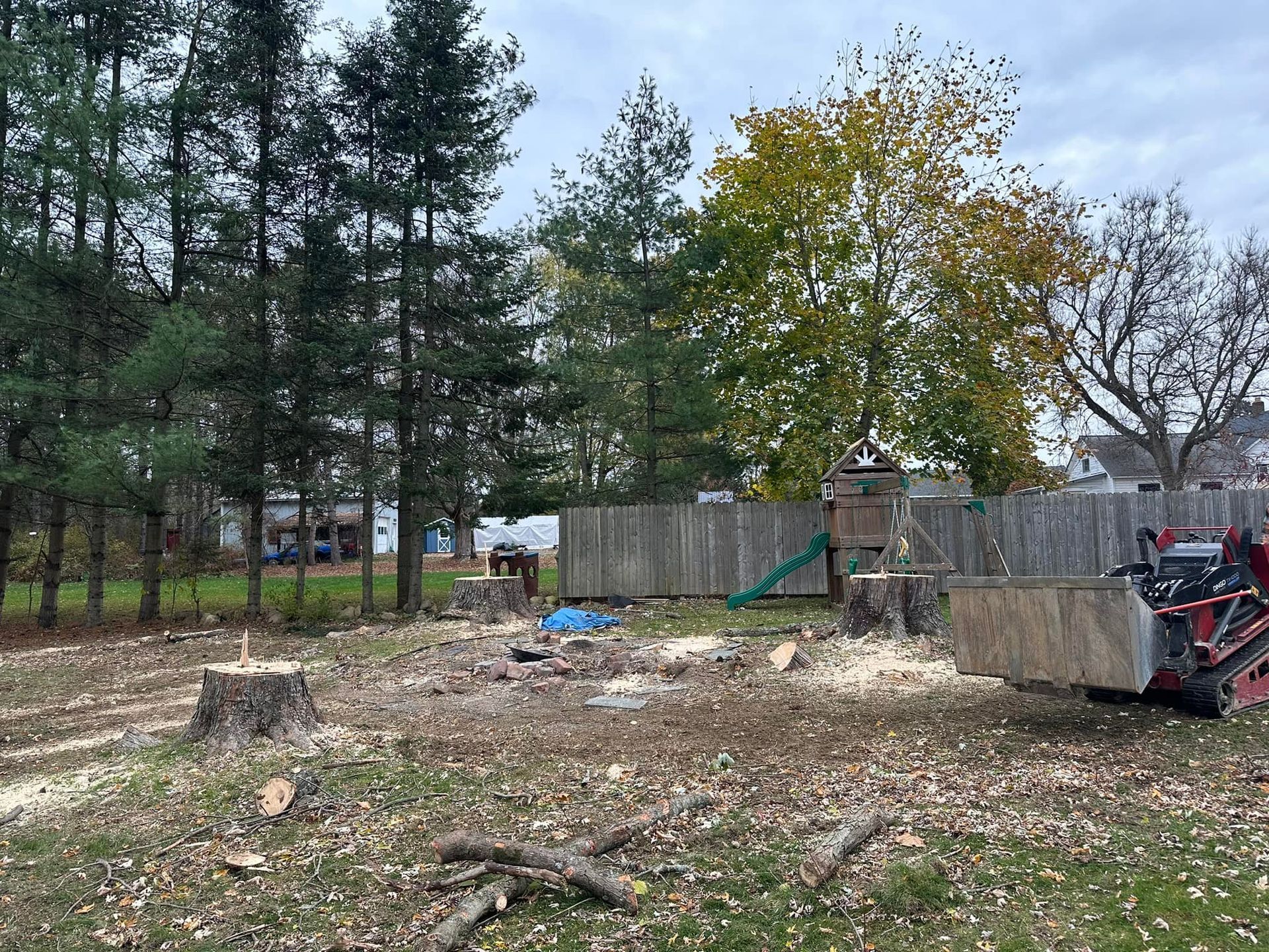 A tractor is cutting down a tree in a yard.