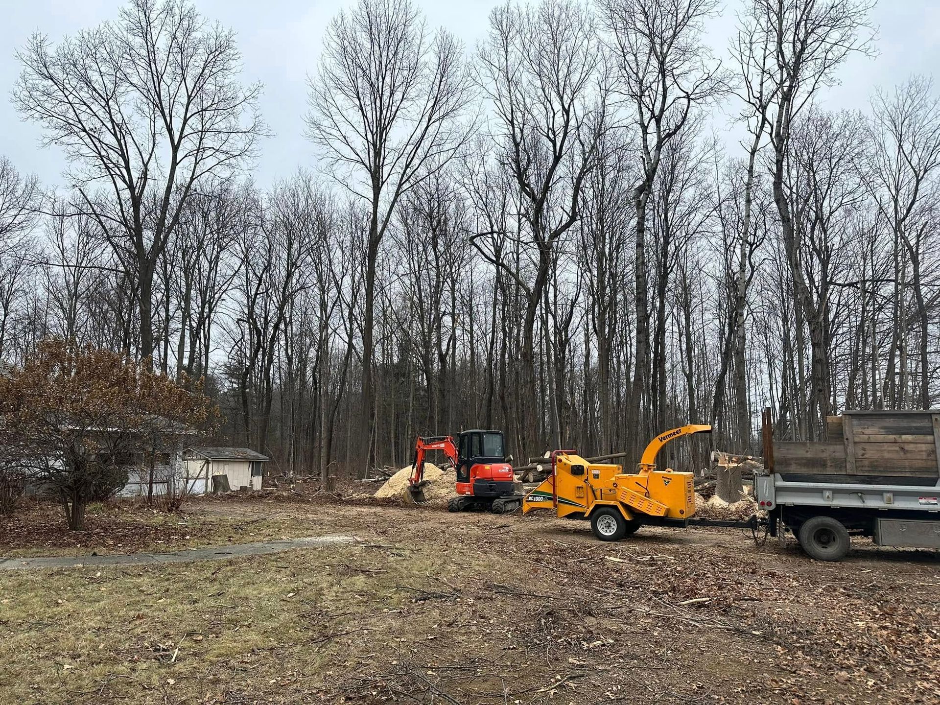 A lot of machinery is parked in a field with trees in the background.