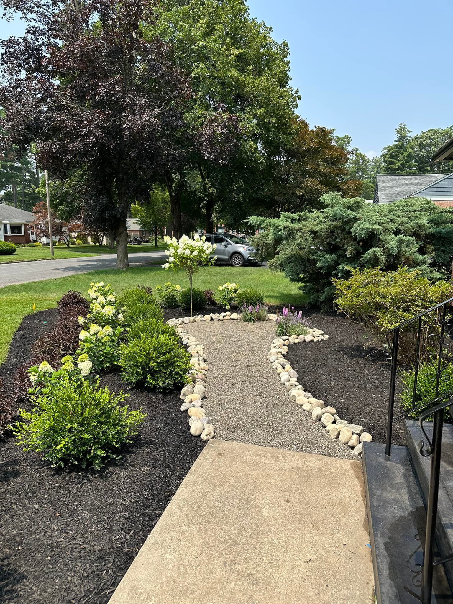 A walkway leading to a house surrounded by trees and bushes.