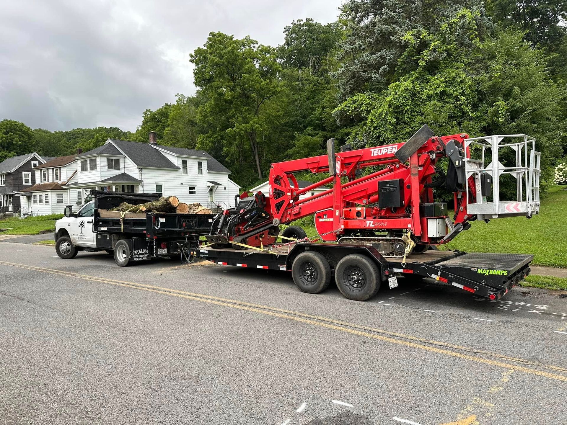A red aerial lift is being towed by a dump truck.