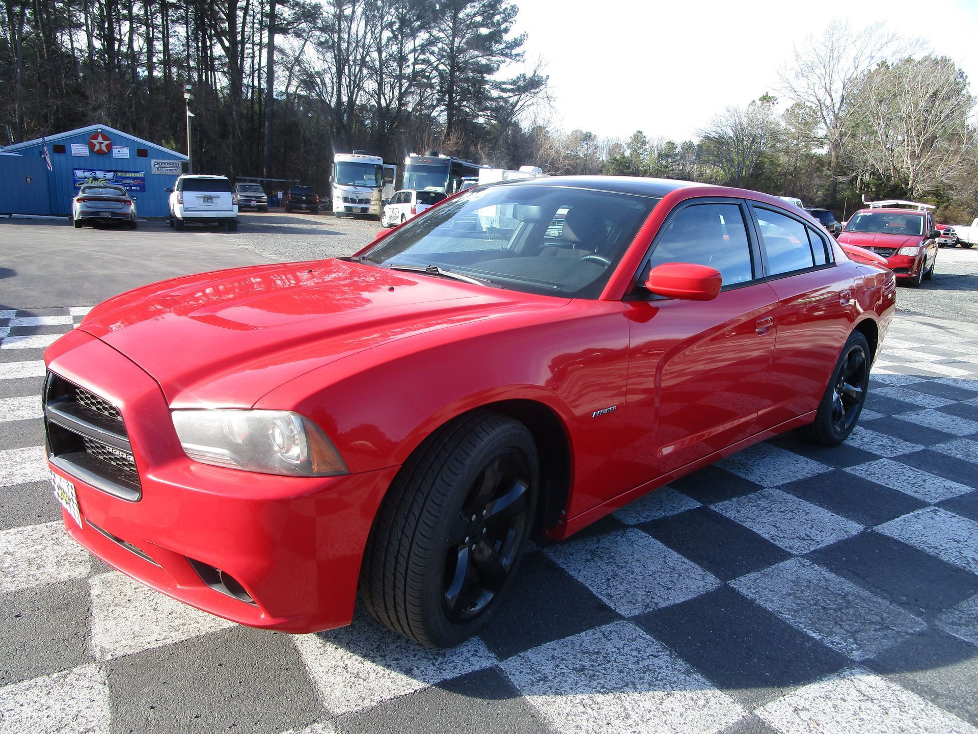 Red Dodge Charger with black wheels parked on a checkered surface.