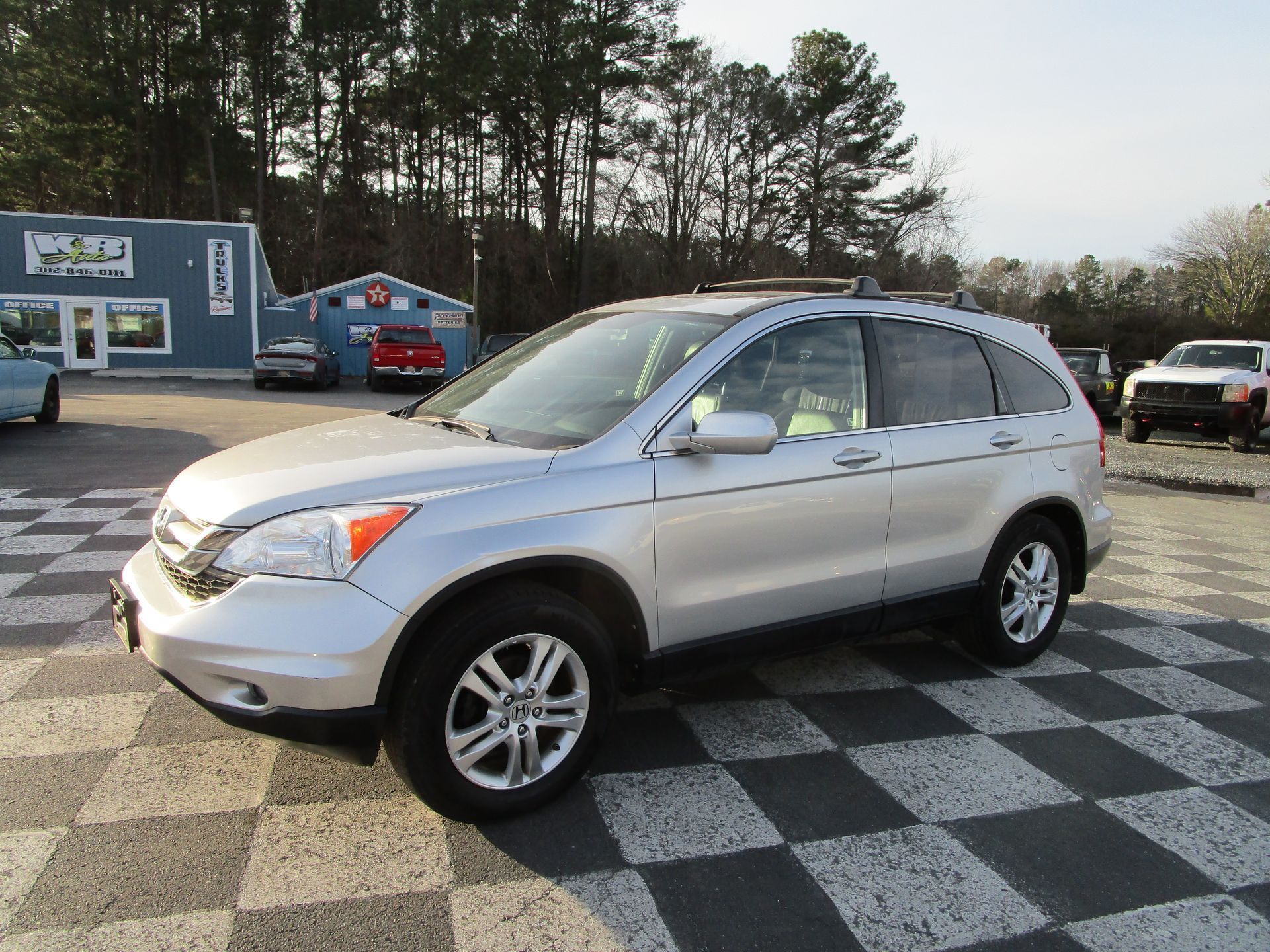 Silver Honda CR-V SUV parked on checkered ground in front of a building on a sunny day.