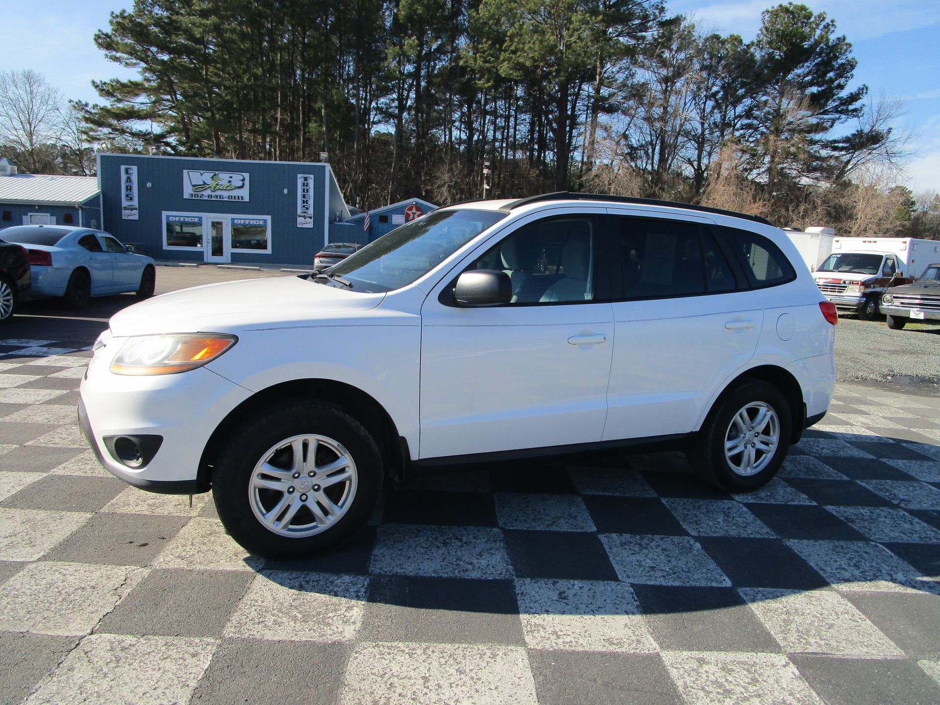 White Hyundai Santa Fe SUV parked on a checkered lot at a car dealership.