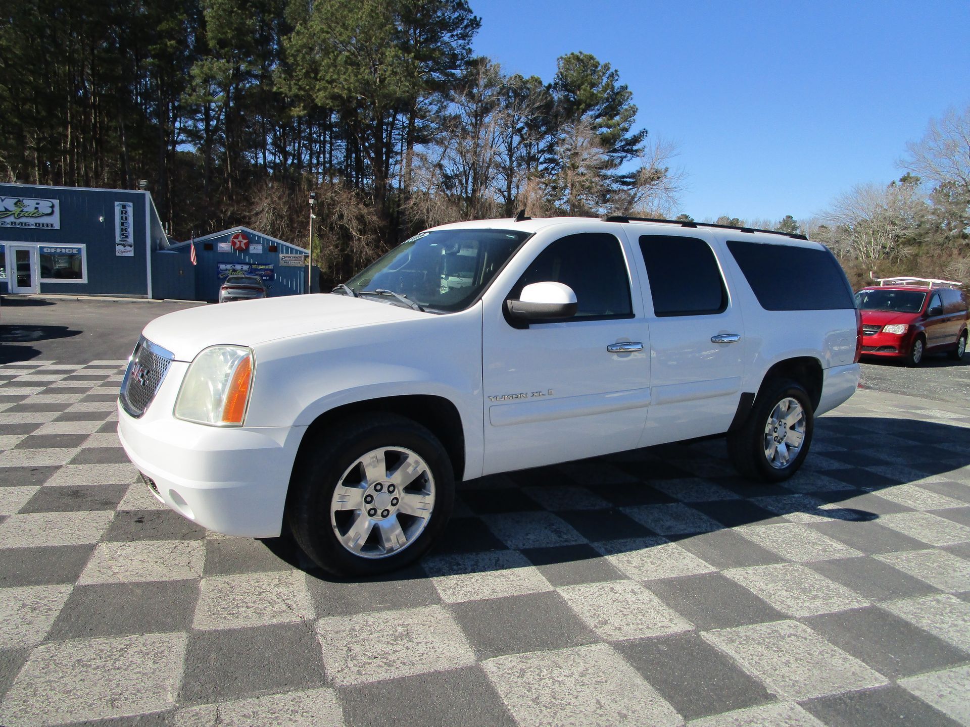 White GMC Yukon SUV parked on a checkered surface under a clear sky.