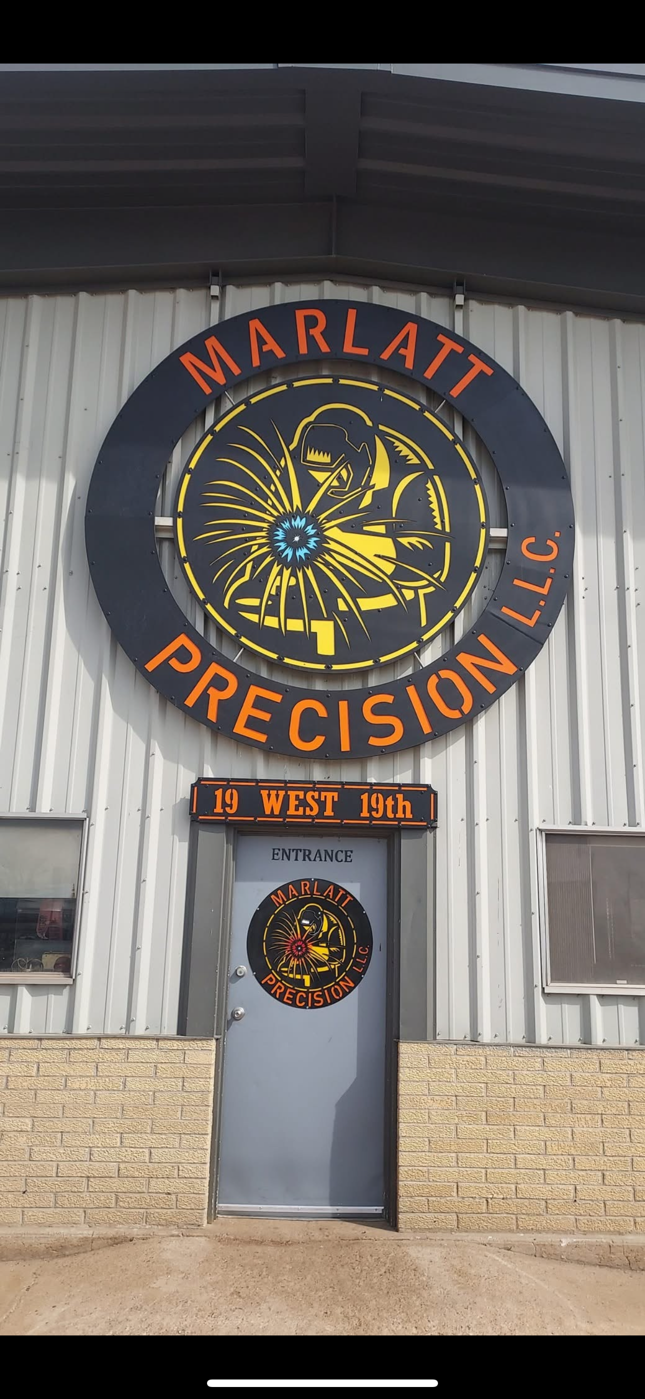 A large sign on the side of a building says marlatt precision llc.