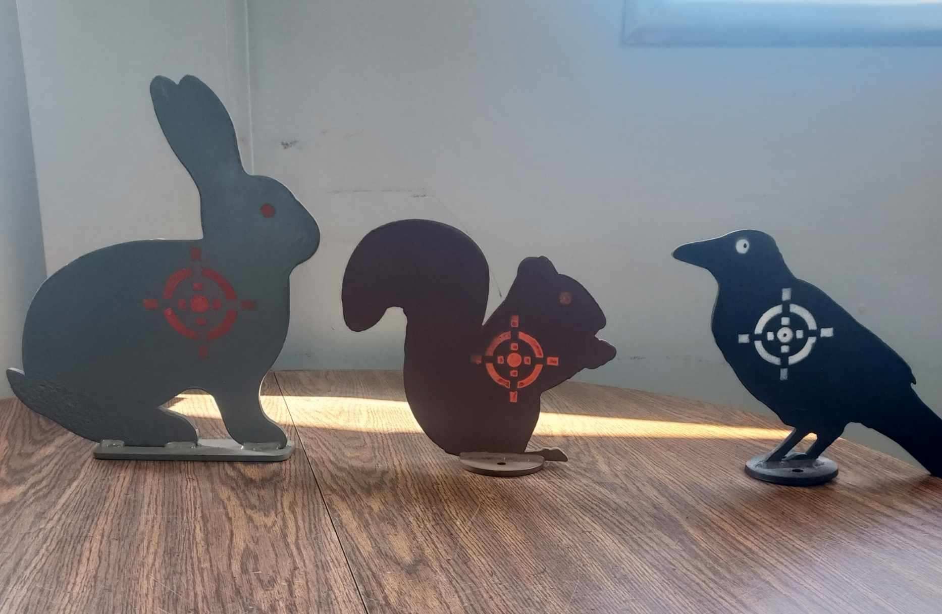 A rabbit , squirrel and crow are sitting on a wooden table.