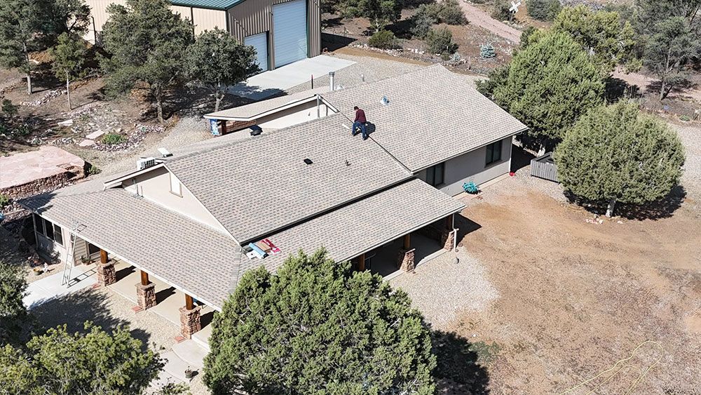 An aerial view of a house with a roof that is surrounded by trees.