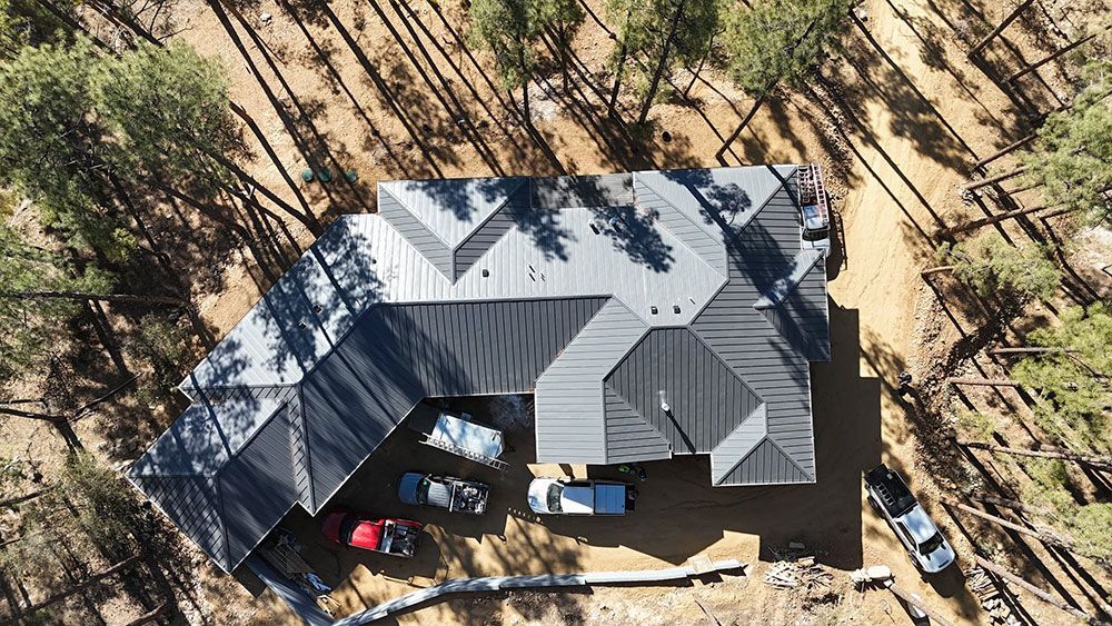 An aerial view of a house in the middle of a forest.