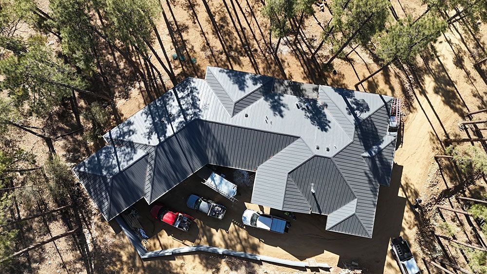 An aerial view of a house in the middle of a forest.