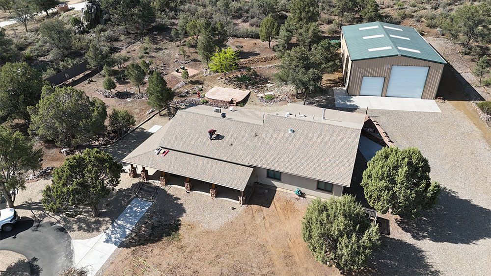 An aerial view of a house in the middle of a desert surrounded by trees.