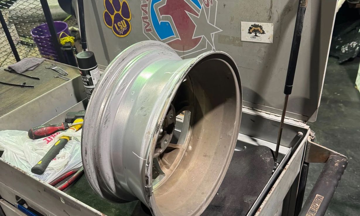 Large metal wheel rim on a workbench in a garage or workshop.