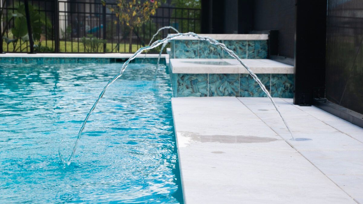 A swimming pool with a fountain in the middle of it.