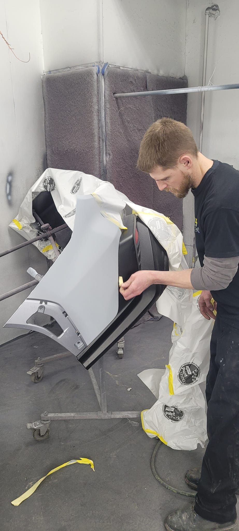 A man is working on a car in a paint booth.