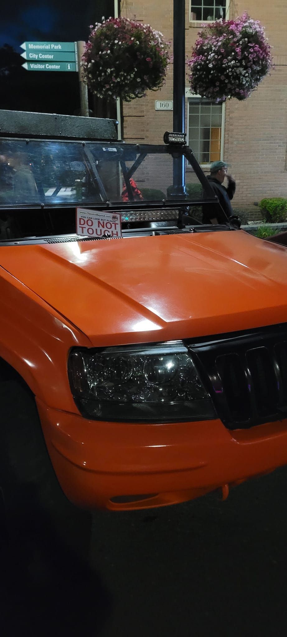 An orange jeep is parked in front of a building at night.