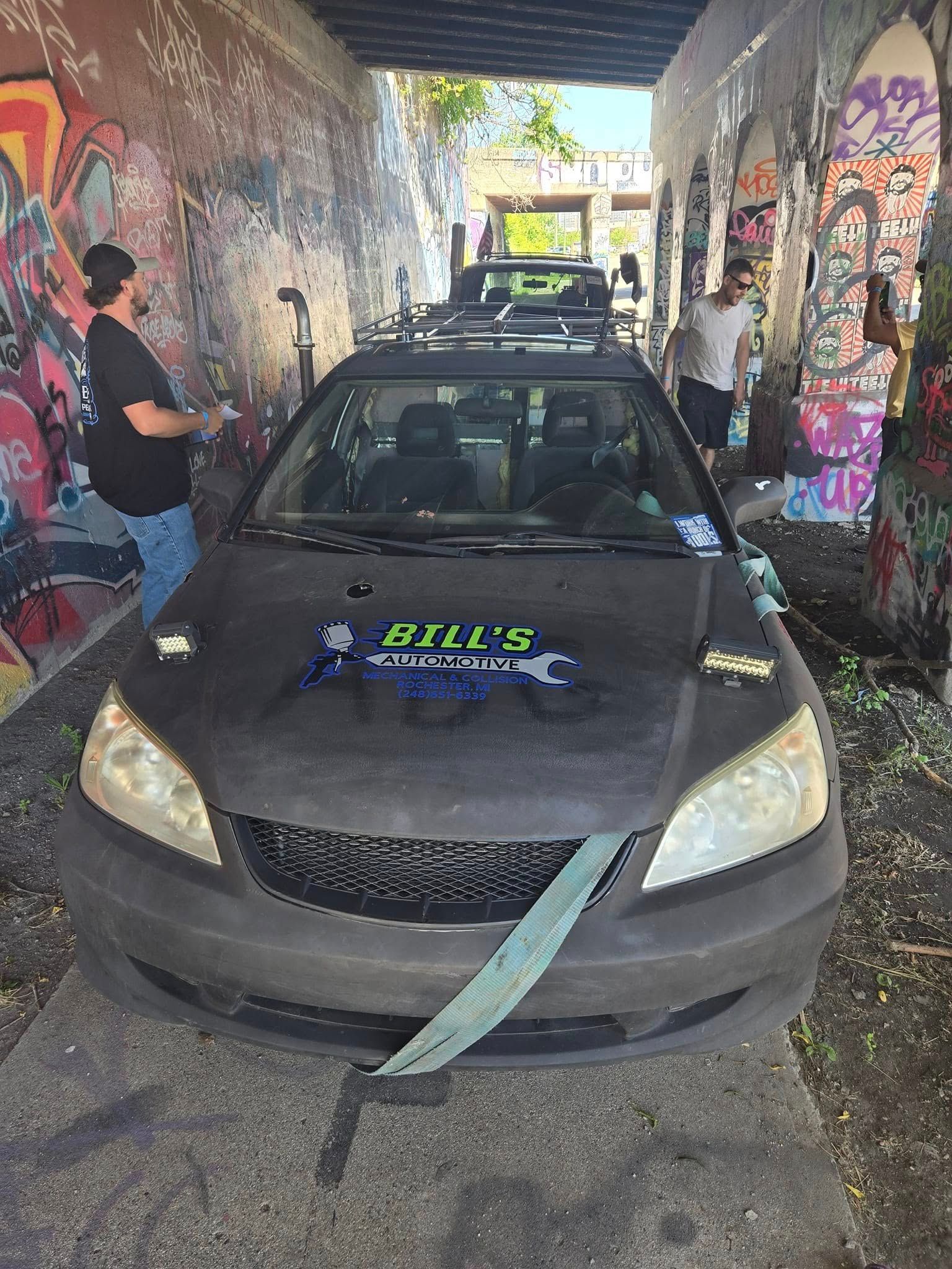 A car is tied up in a tunnel with graffiti on the walls.