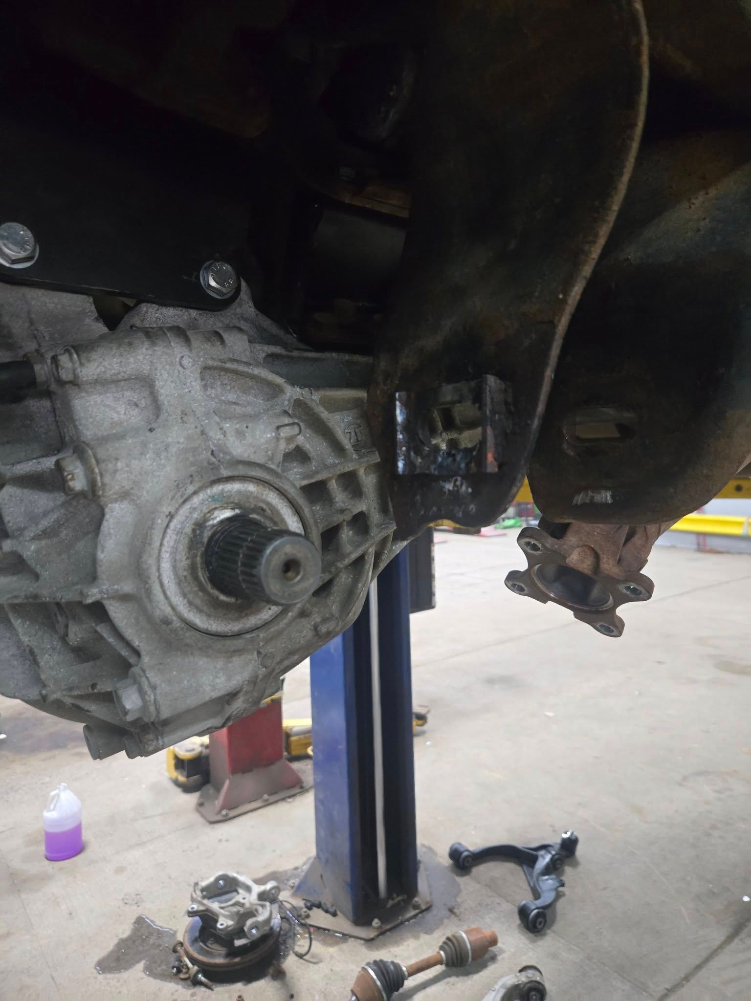 A car is being repaired on a lift in a garage.