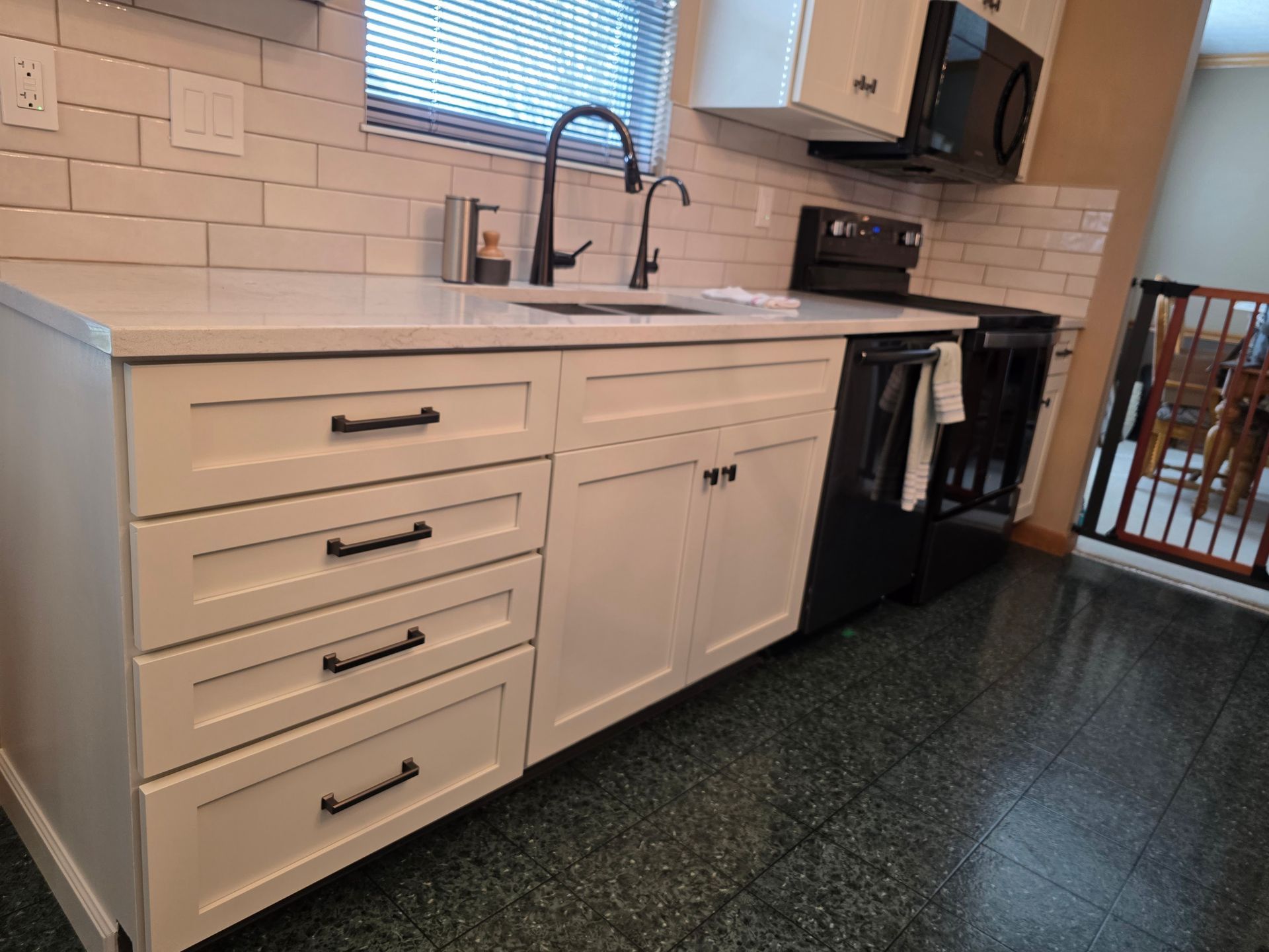 A kitchen with white cabinets , a sink , a stove and a microwave.