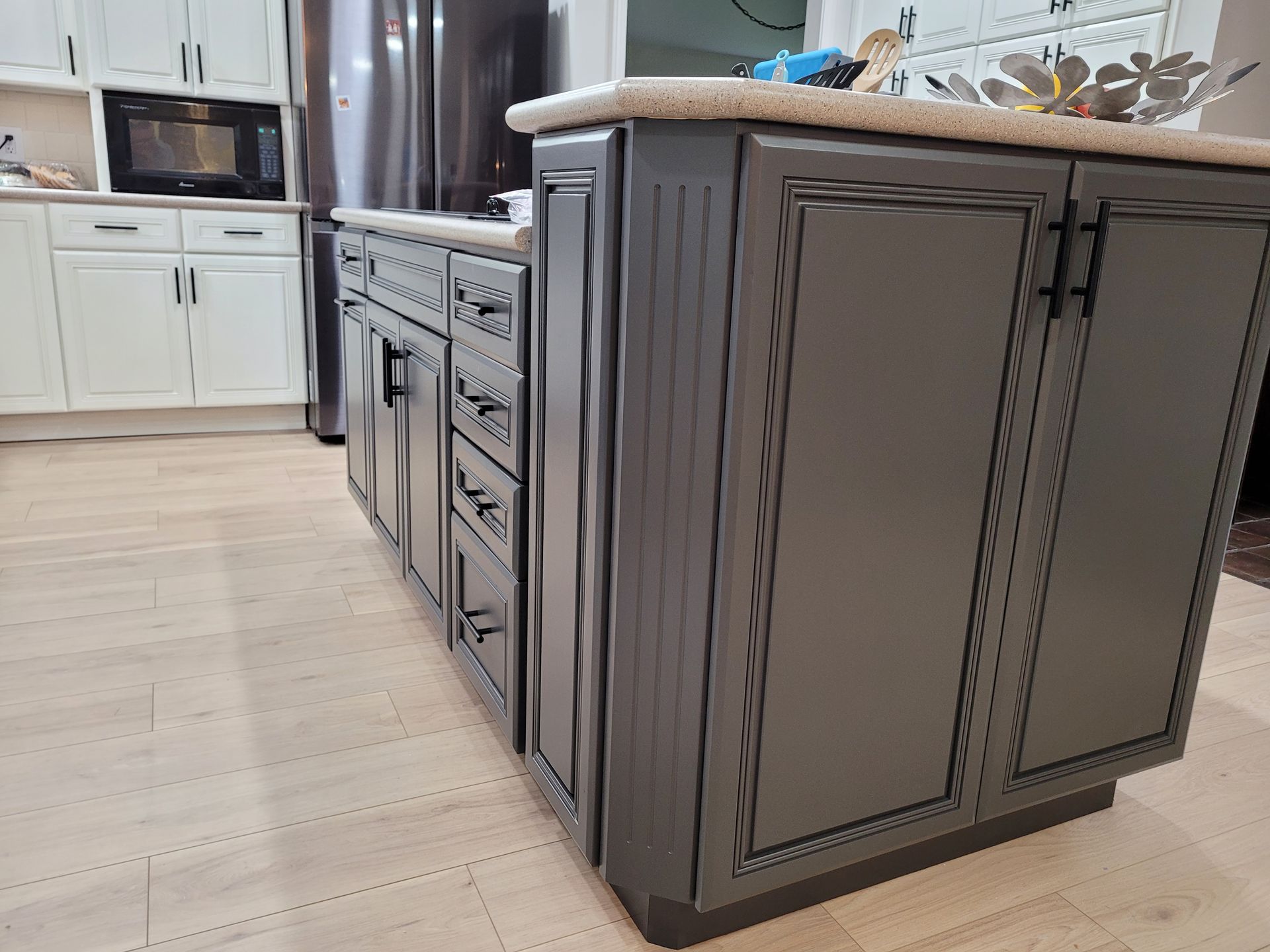 A kitchen with gray cabinets and white cabinets and a large island.