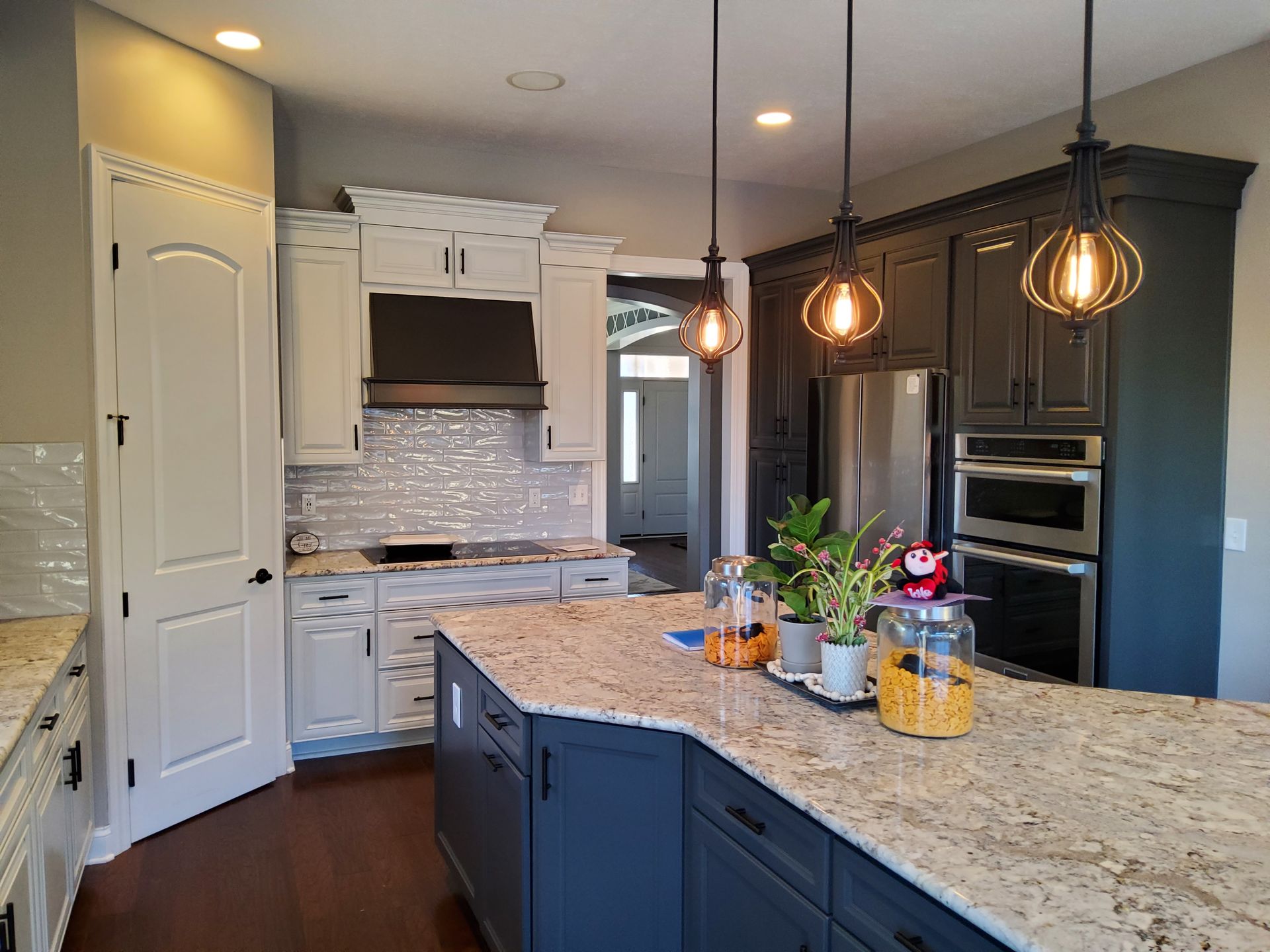 A kitchen with blue cabinets , granite counter tops , stainless steel appliances and a large island.
