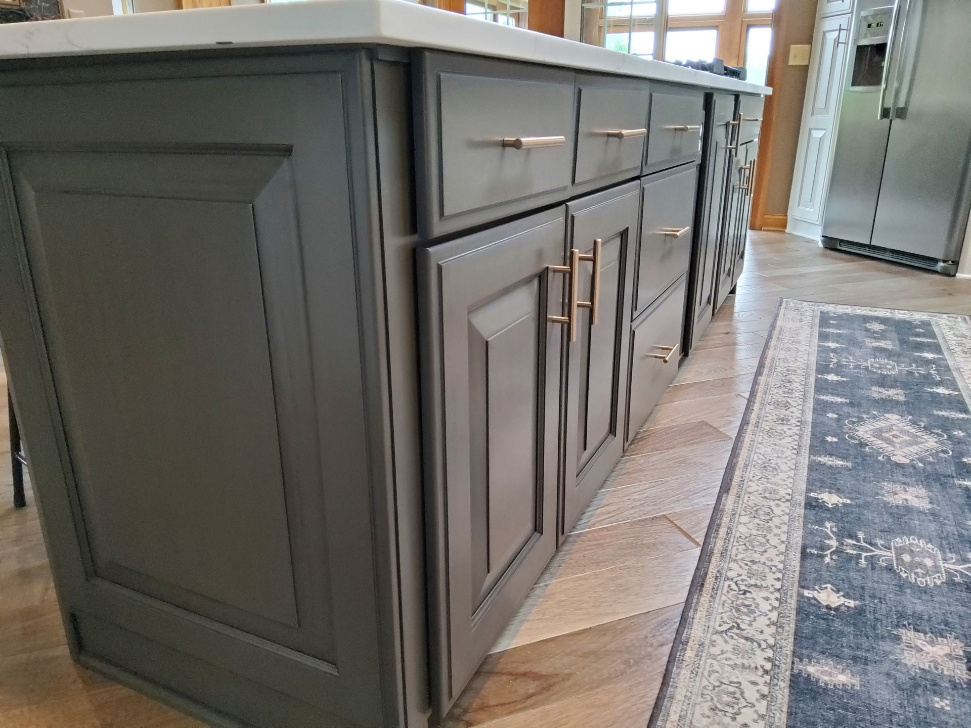 A kitchen with gray cabinets and drawers and a rug on the floor.