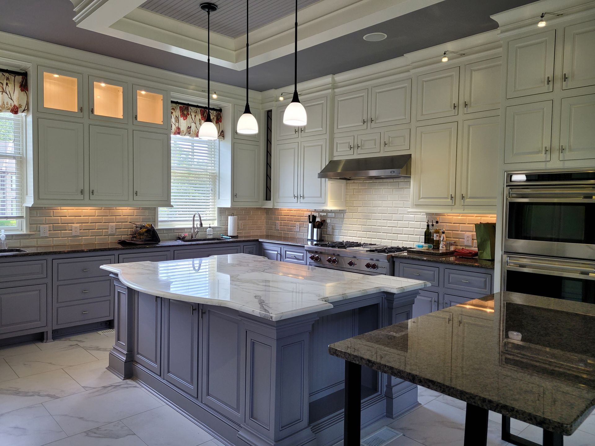 A kitchen with gray cabinets and a large island in the middle.